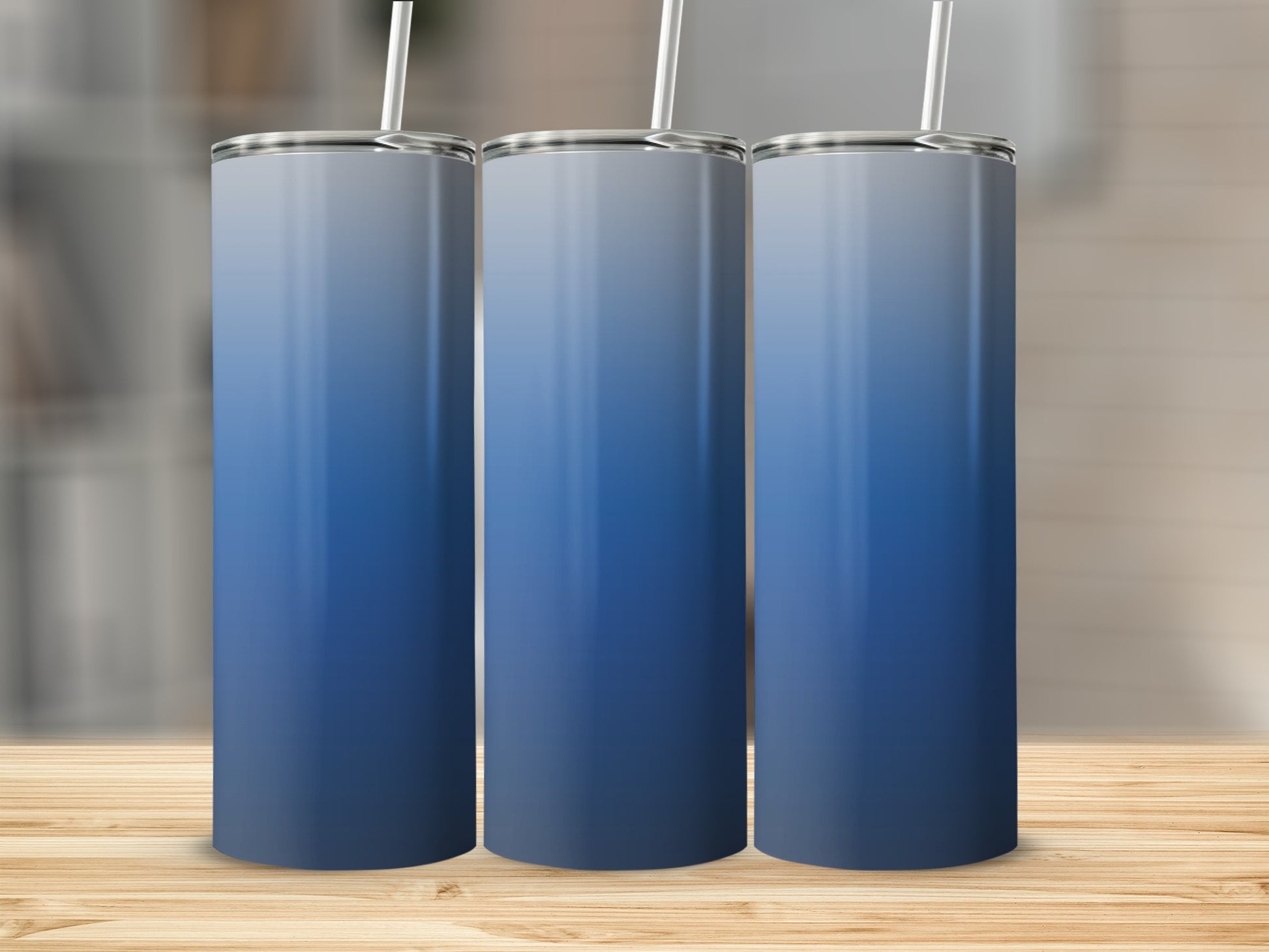 Three blue gradient tumblers with white straws on a wooden surface.