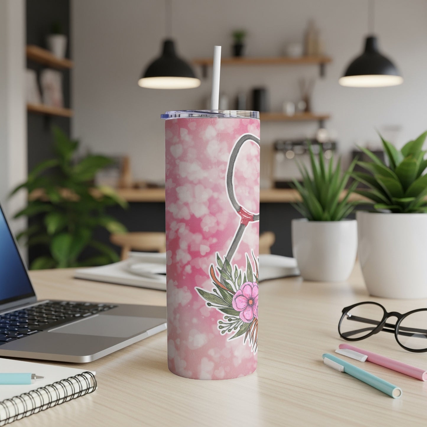 Pink patterned tumbler with floral accent on desk.