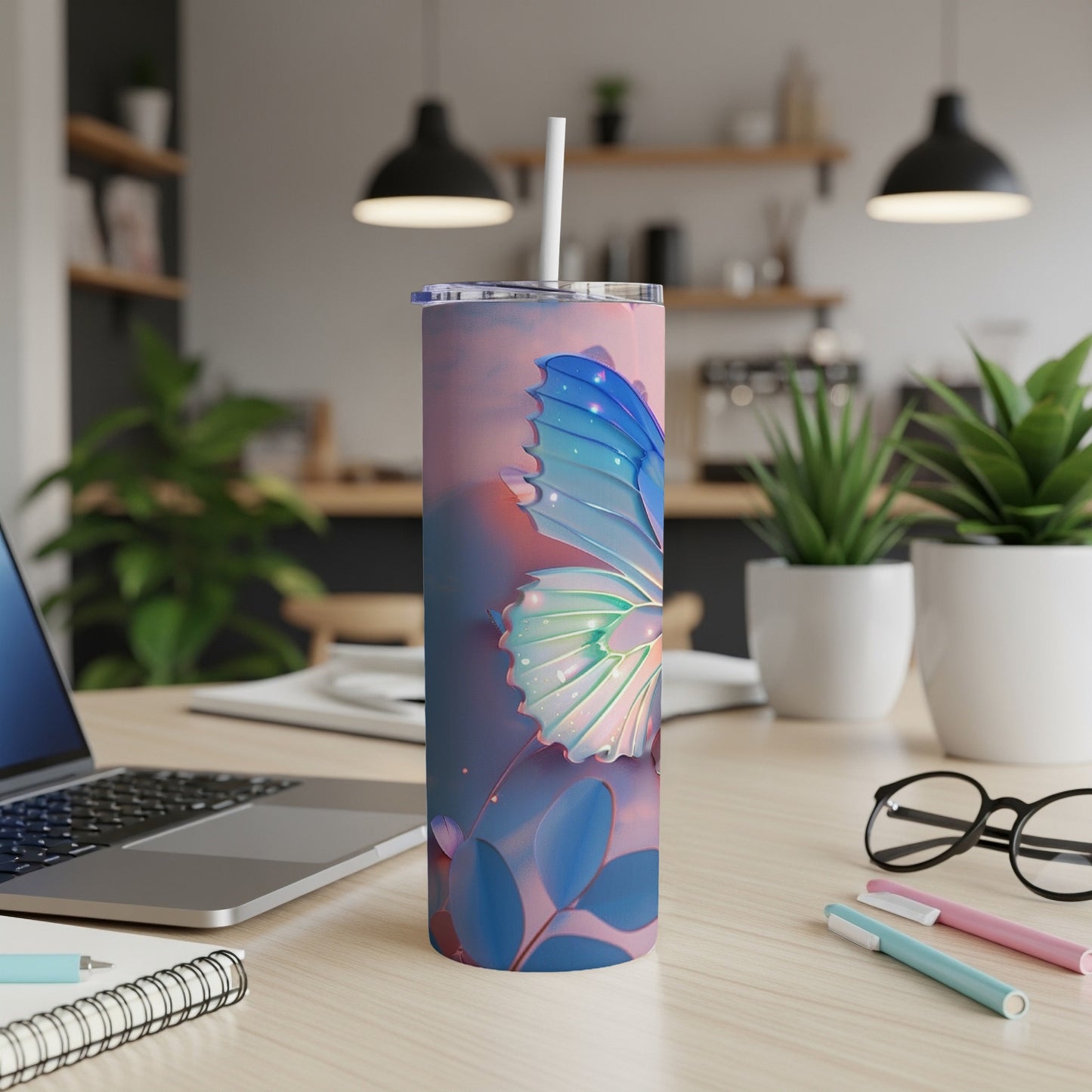 Blue and pink butterfly design on a tall, slim tumbler with a straw, on a desk.