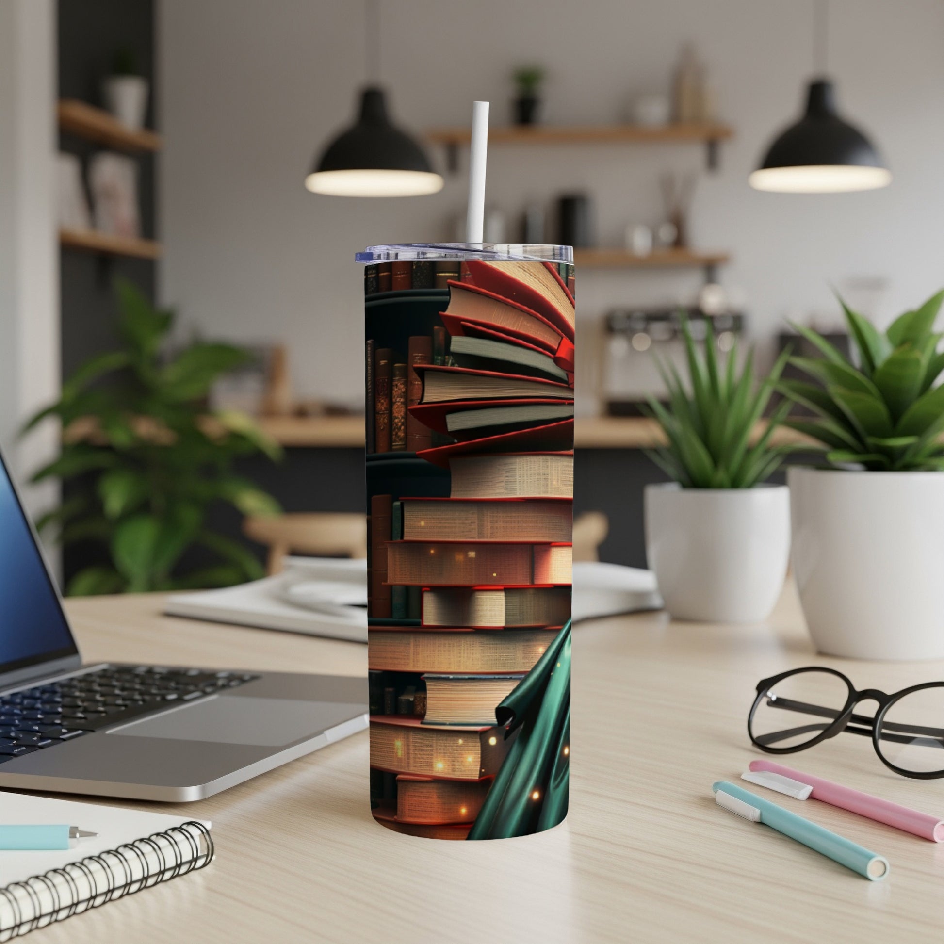 Tall tumbler with stack of open books and green scarf on desk.
