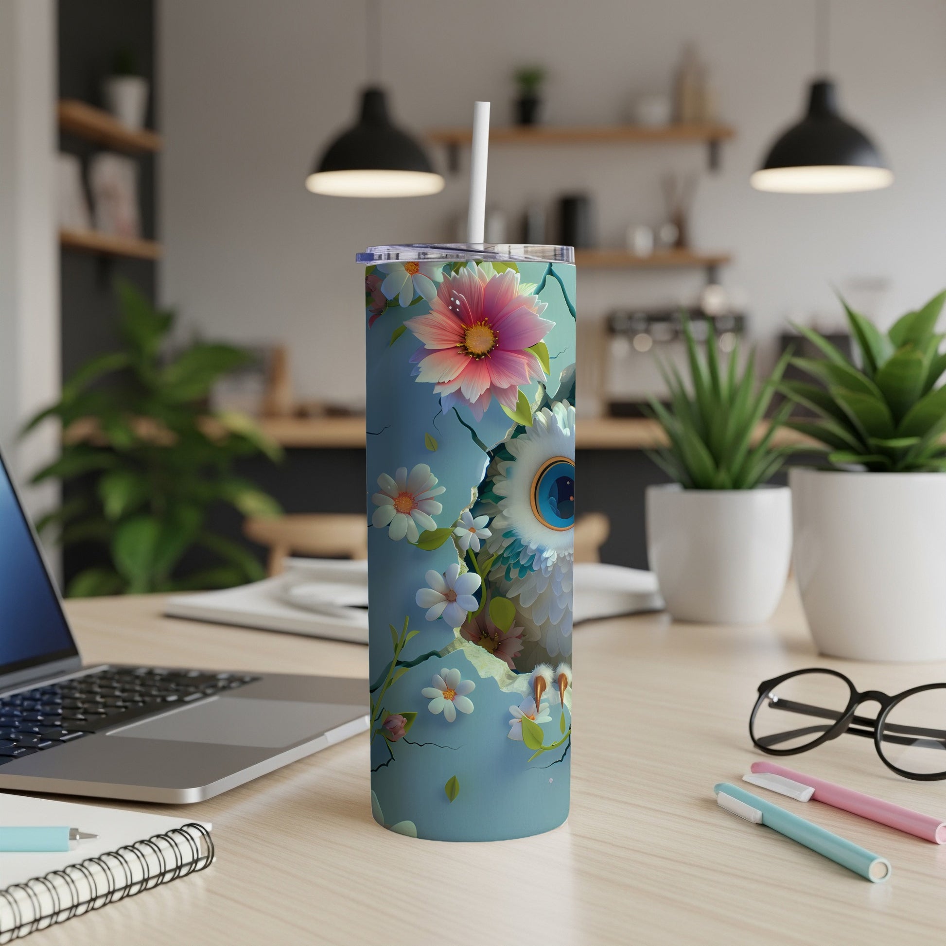 Blue tumbler with owl and floral design, on desk with laptop and pens.