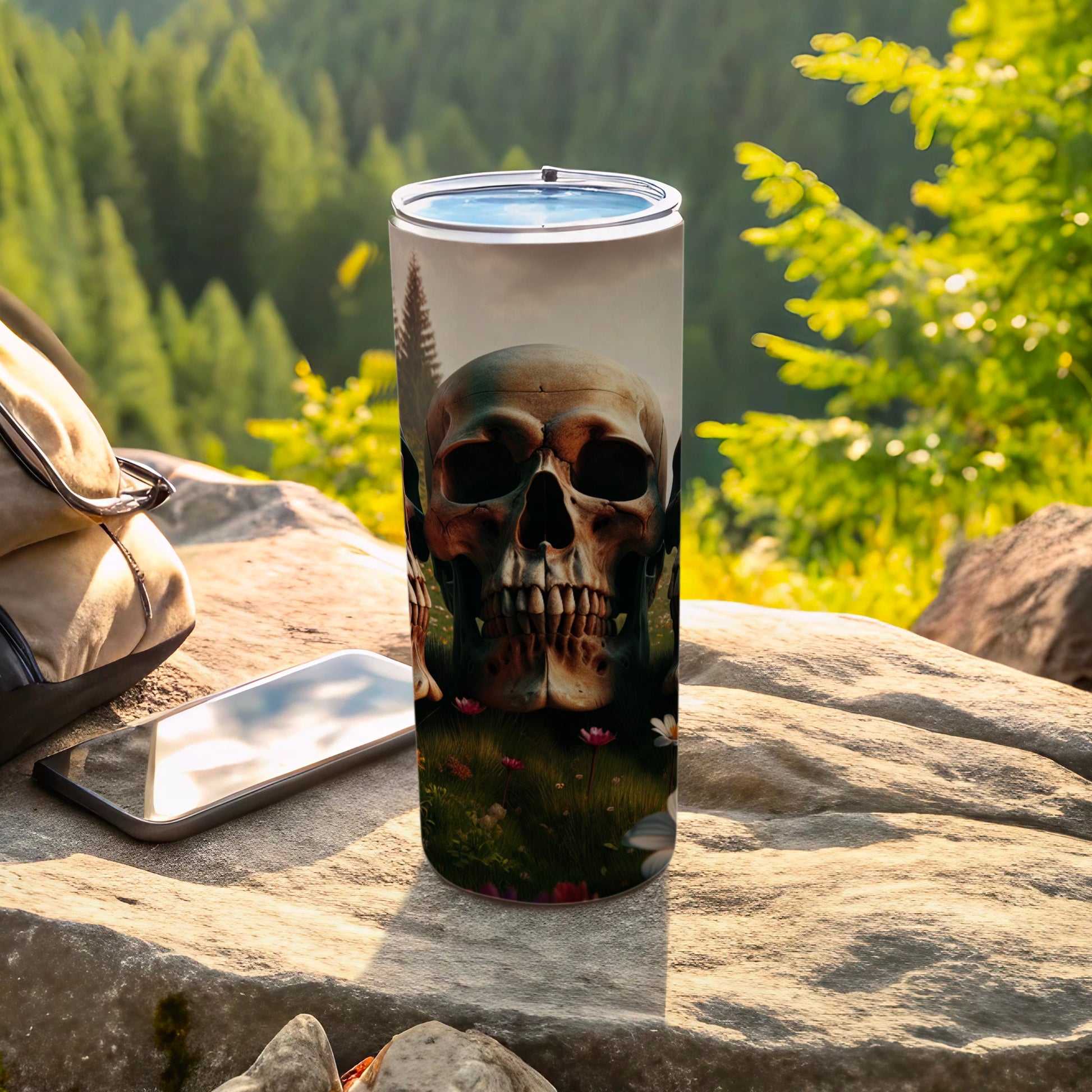 Tumbler with skull and floral design, on a rock outdoors.