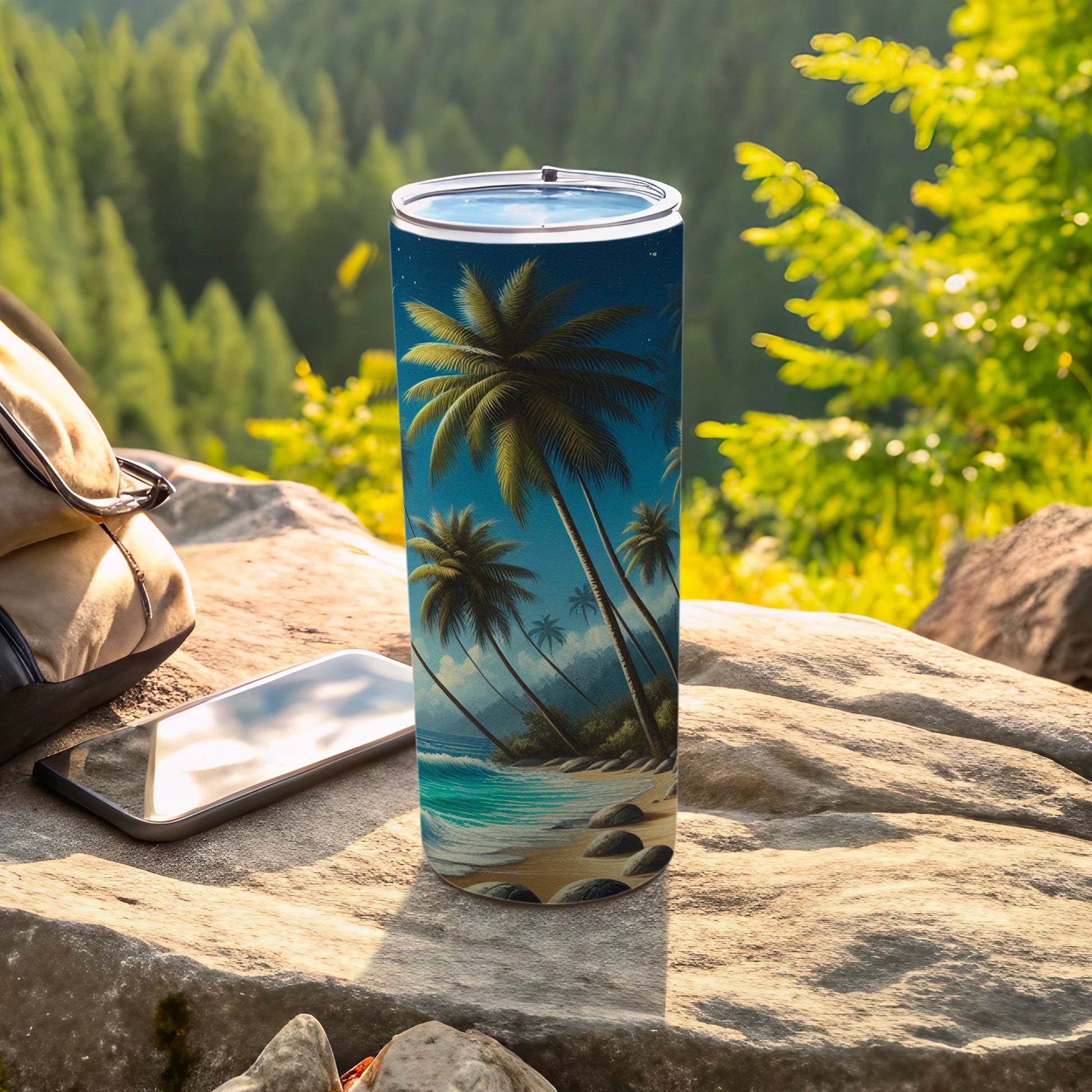 Tall tumbler with palm trees and ocean scene design, next to phone.