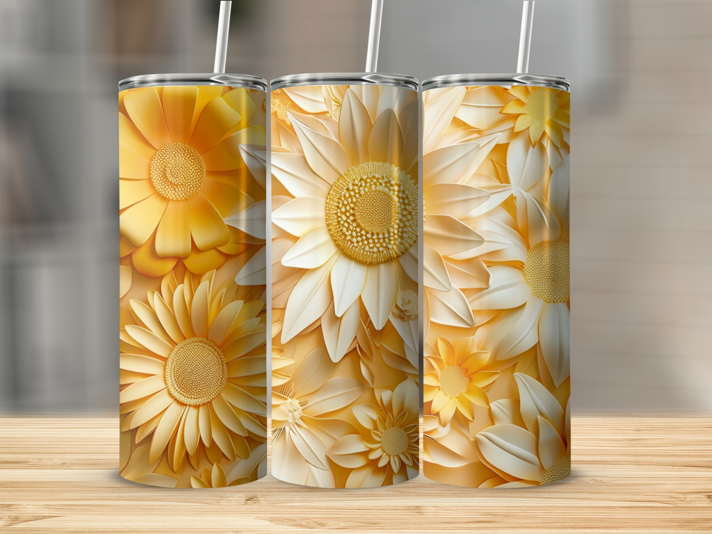 Three yellow and white floral tumblers with straws on a wooden surface.