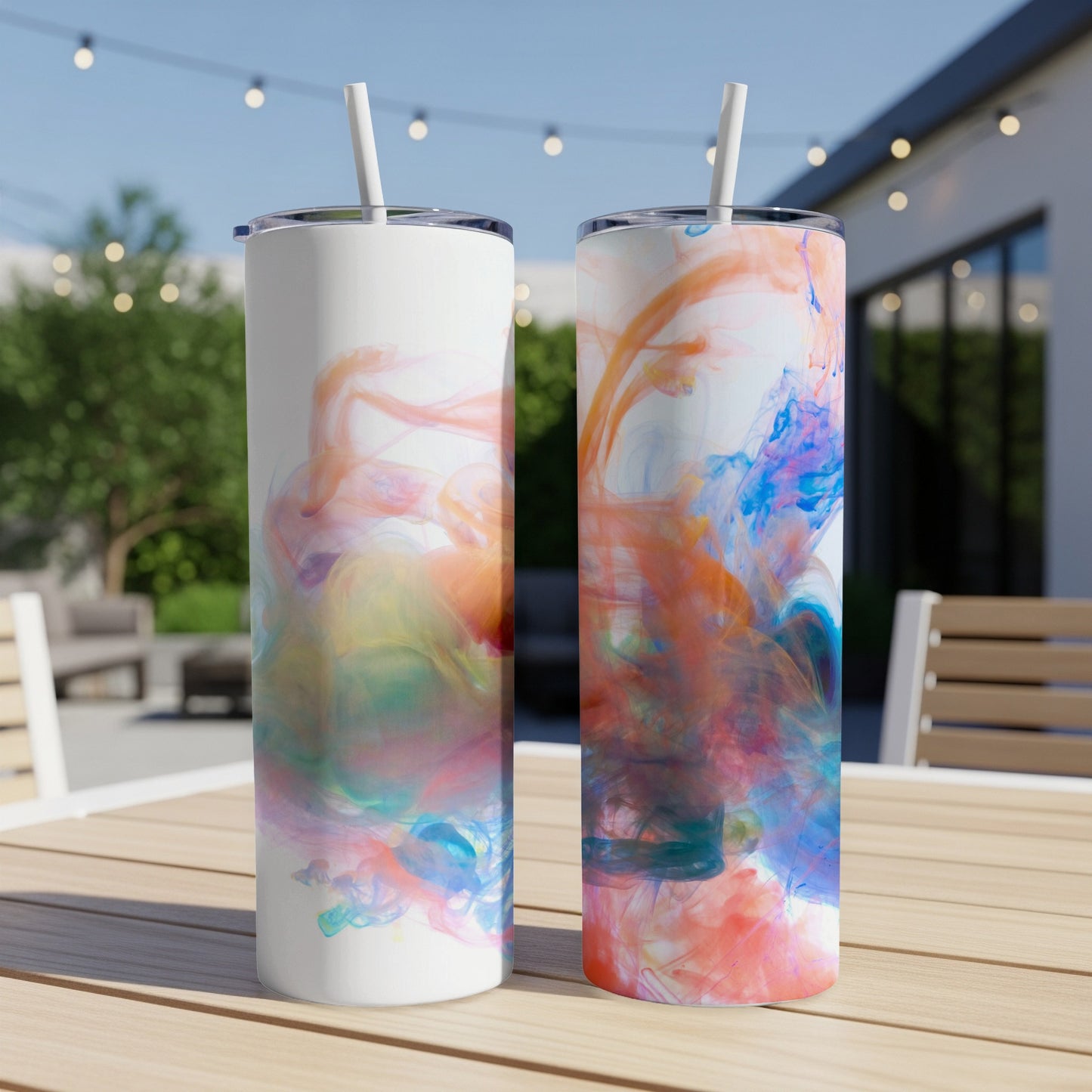 Two tumblers with colorful watercolor-like swirls on a wooden table outdoors.
