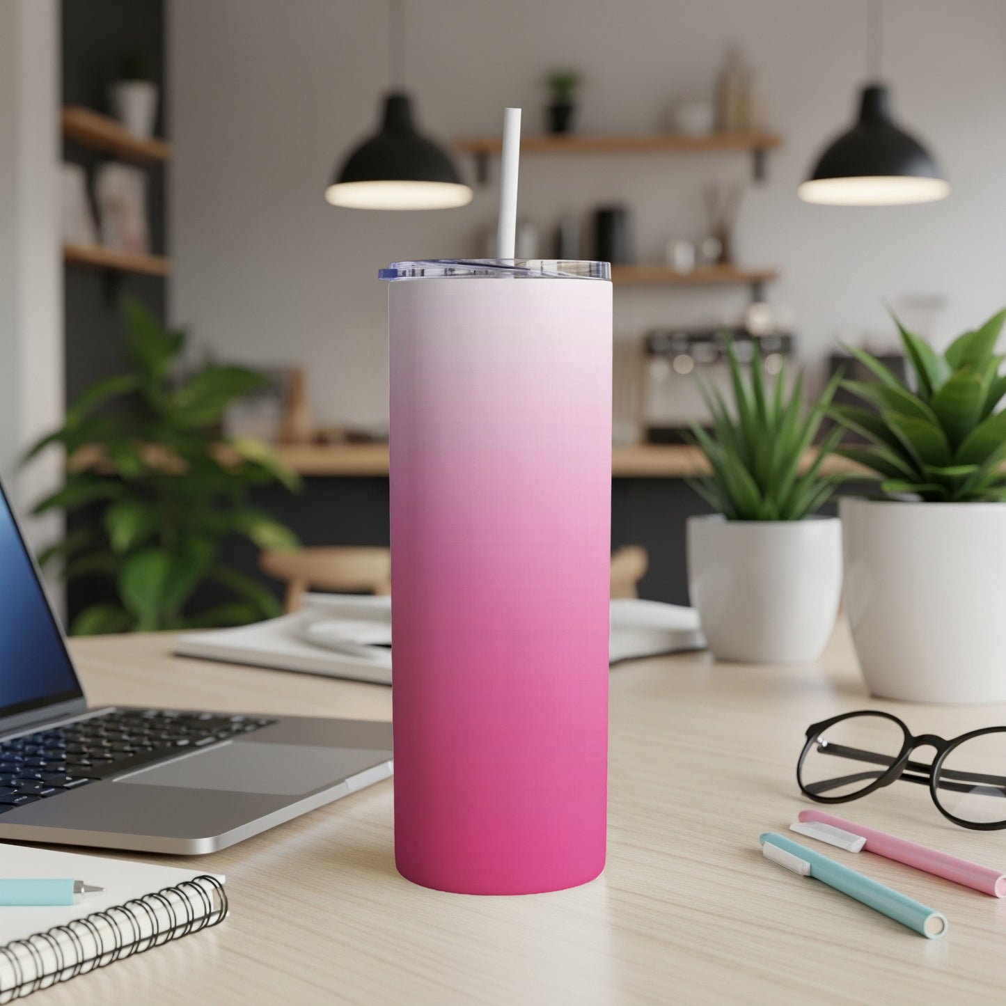 Pink gradient skinny tumbler with straw on a desk.