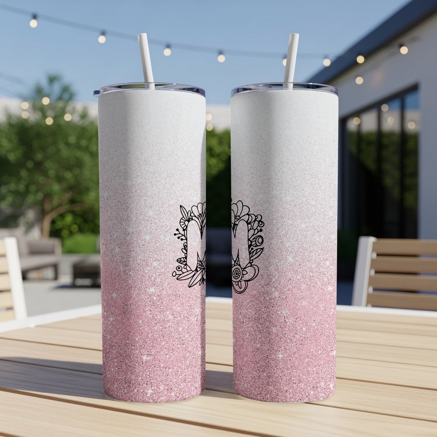 Two tall tumblers with pink glitter gradient and floral letter "M" design.
