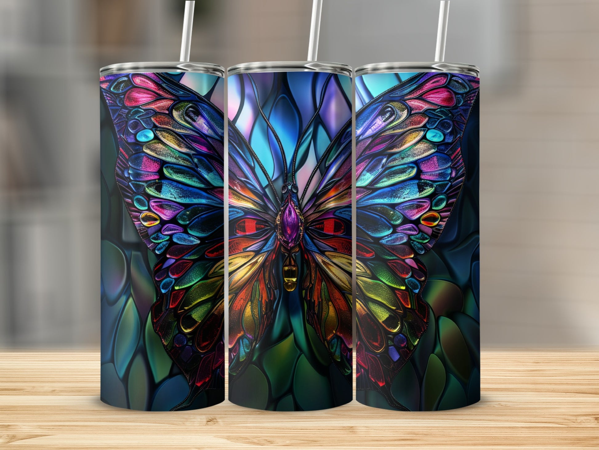 Three stained-glass butterfly tumblers with colorful wings on a wooden surface.