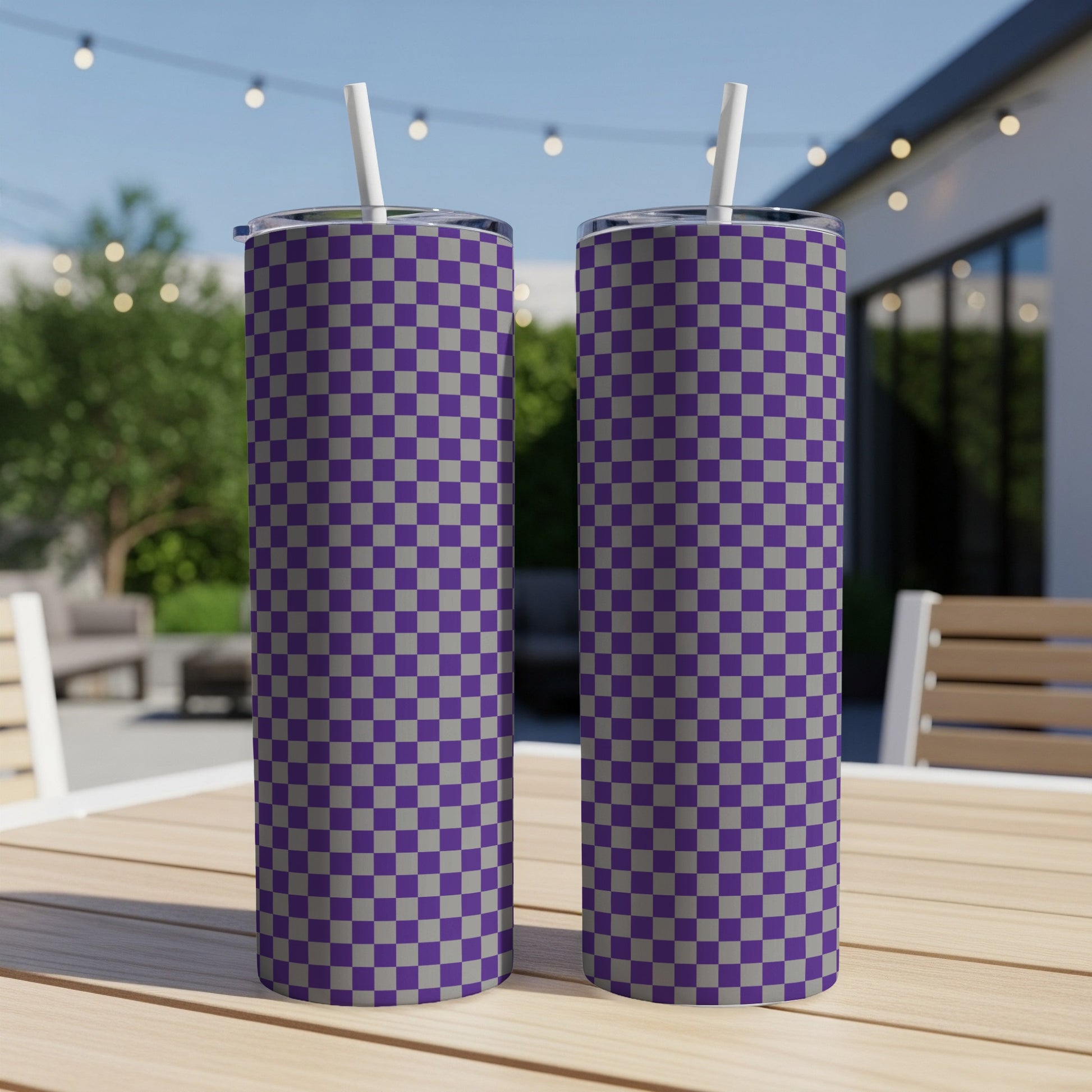 Two purple and gray checkered tumblers with straws on a wooden table.
