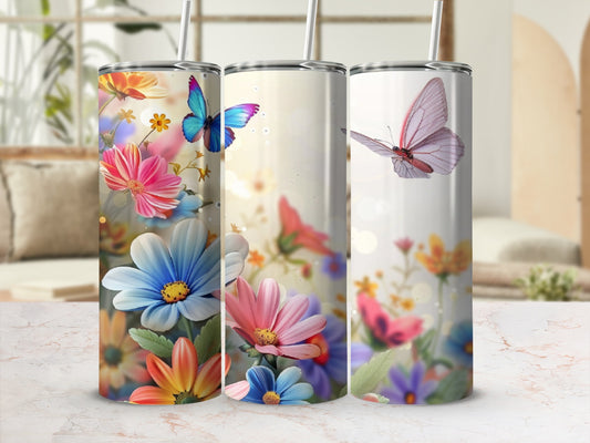Three floral tumblers with butterfly designs on a marble surface.