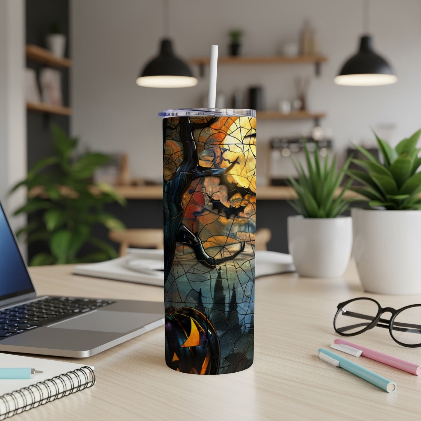 Halloween themed tumbler with pumpkin, bats, and spooky scene on a desk.
