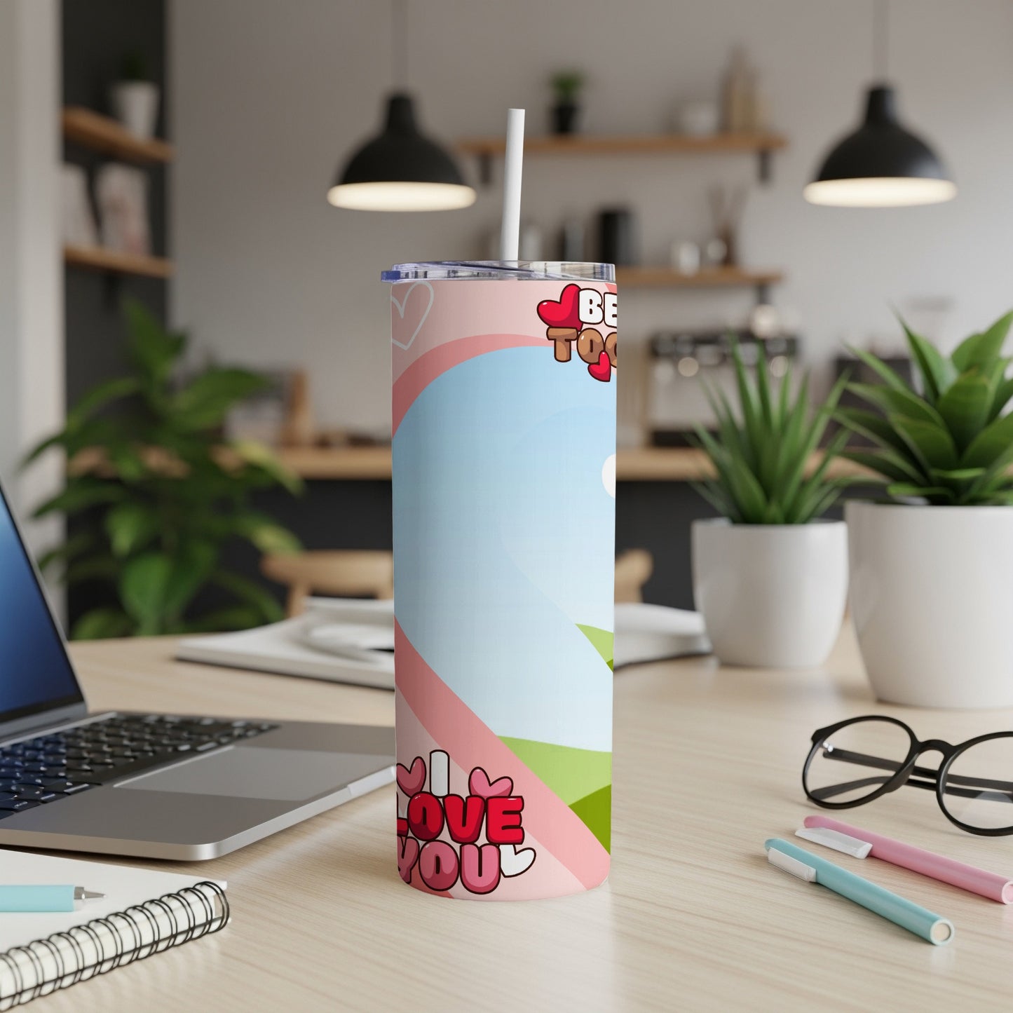 Pink tumbler with "I LOVE YOU" and hearts design on a desk.
