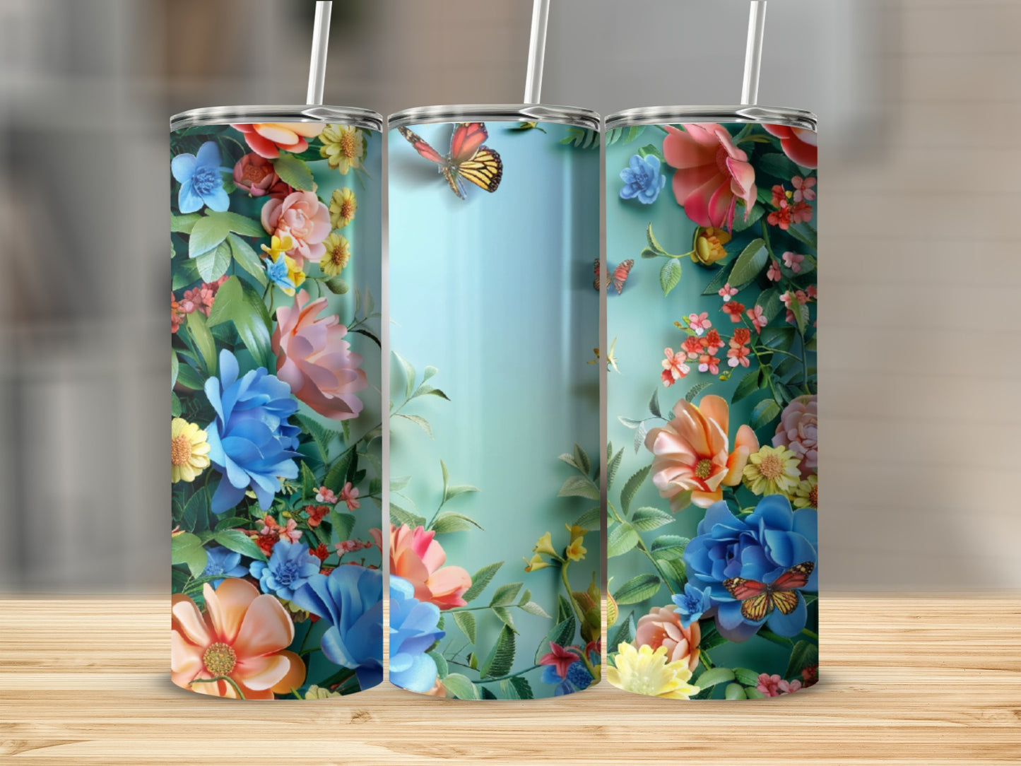 Three tumblers with colorful floral and butterfly designs stand on a wooden surface.