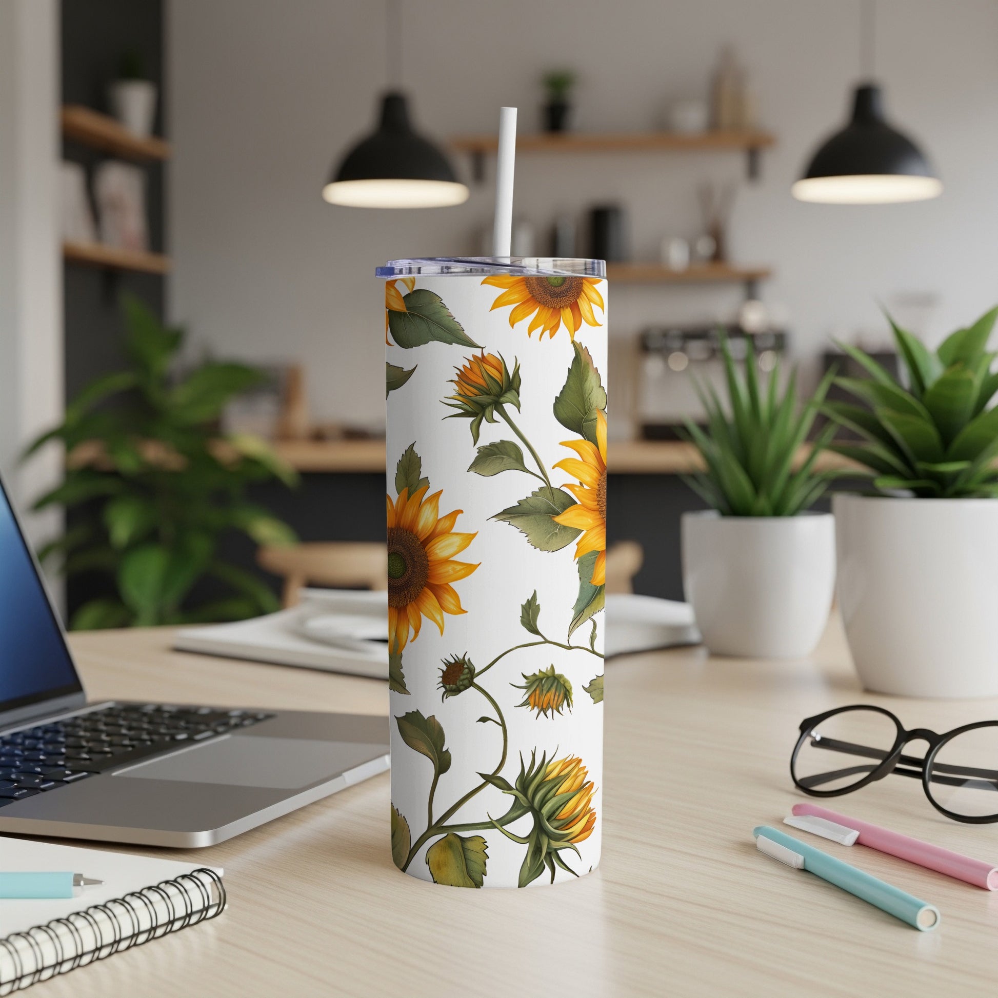 White tumbler with sunflowers and green vines, on a desk.