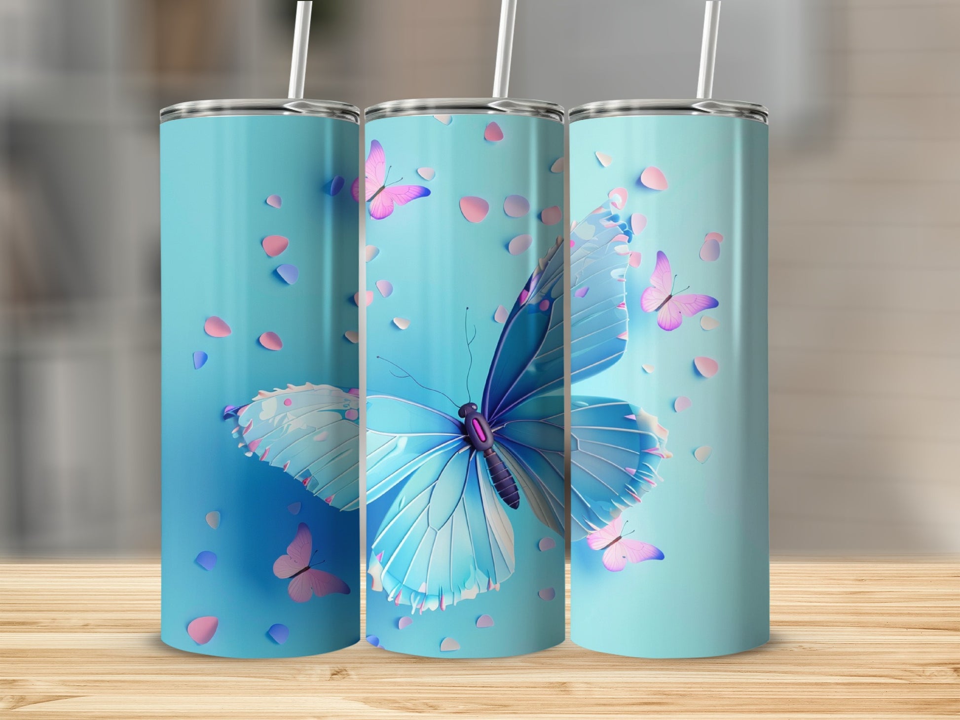 Three blue tumblers with butterflies and pink petals against a blurred background.