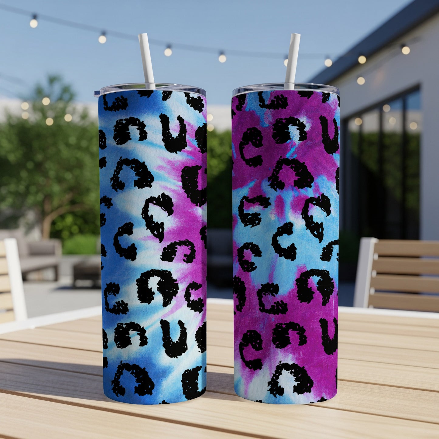 Two tumblers with tie-dye and leopard print designs stand on a wooden table.