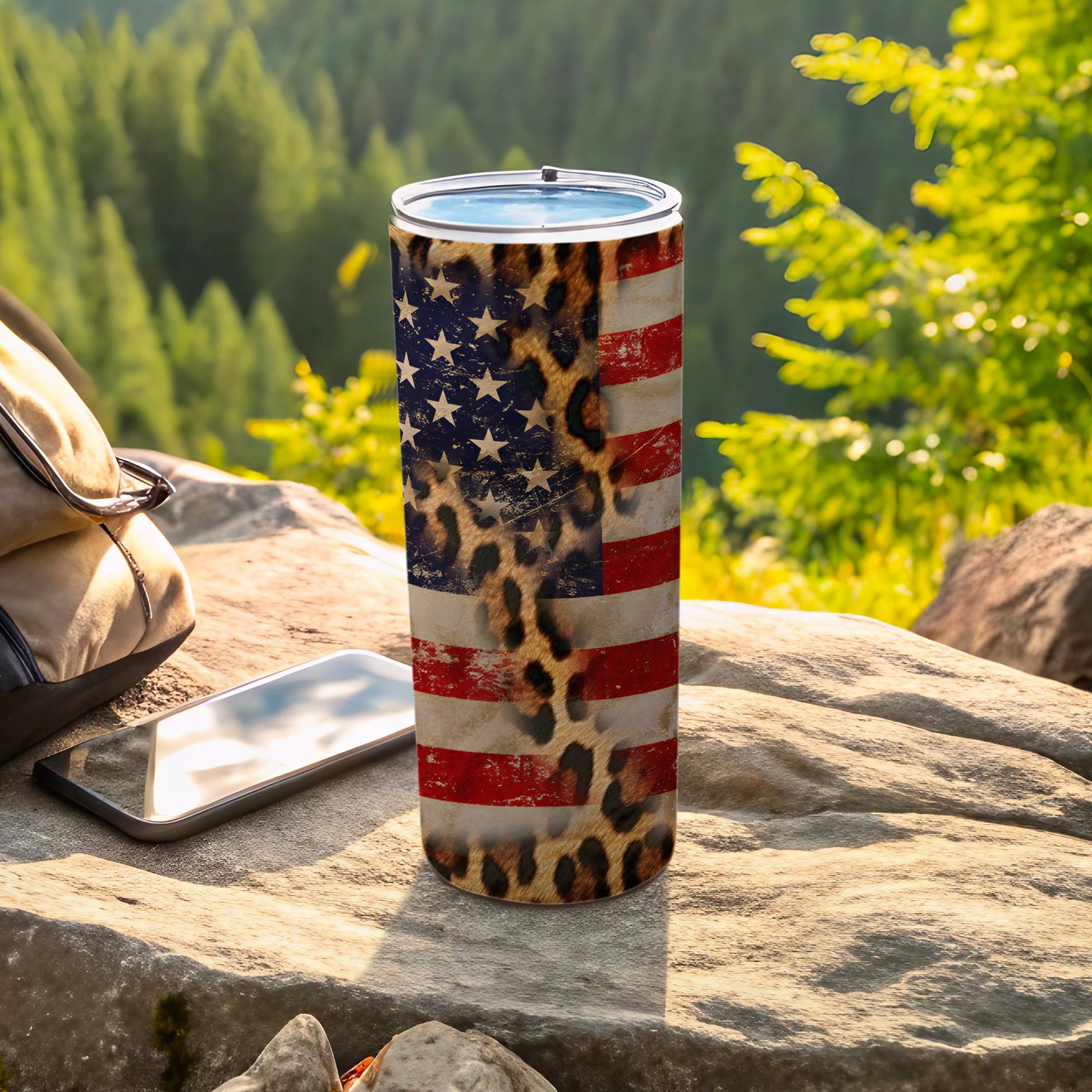 American flag and leopard print tumbler with phone and backpack outdoors.