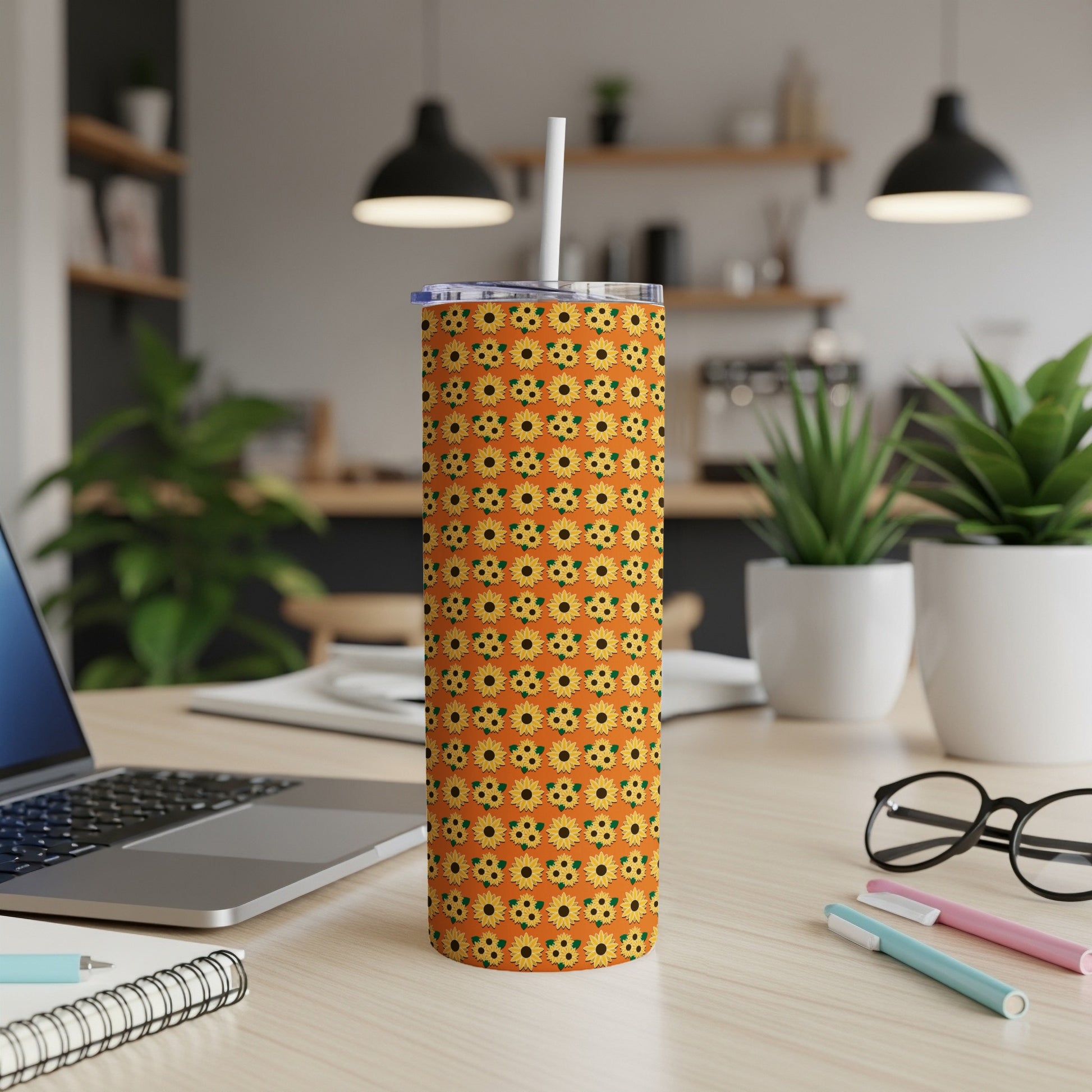 Orange tumbler with a repeating sunflower pattern and white straw.