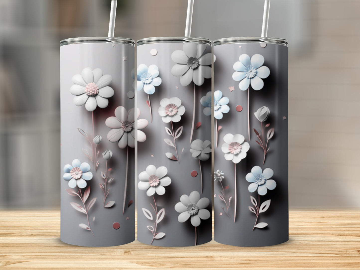 Three gray tumblers with pink and blue floral designs on a wooden surface.