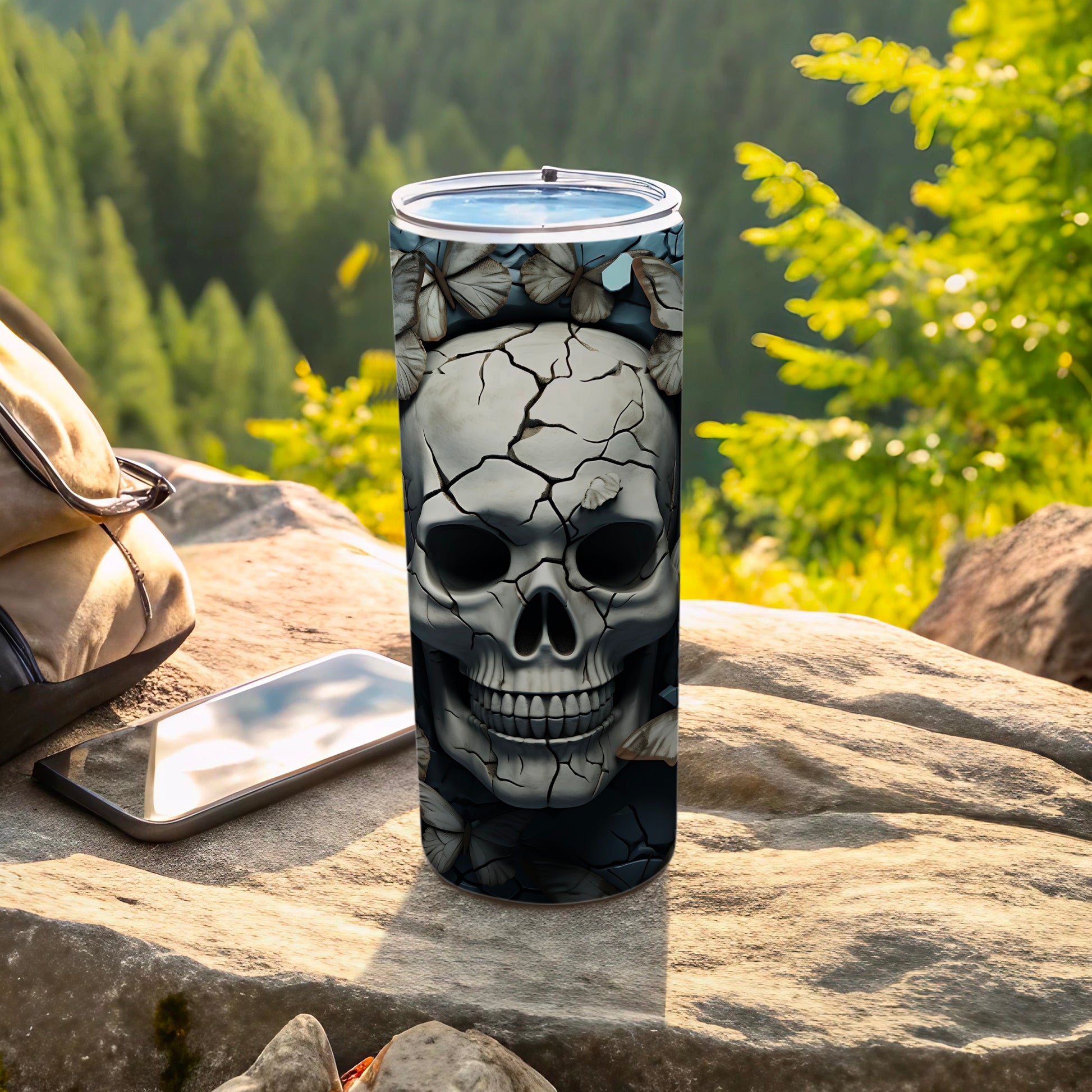 Skull and butterflies design on a travel tumbler with phone and backpack.