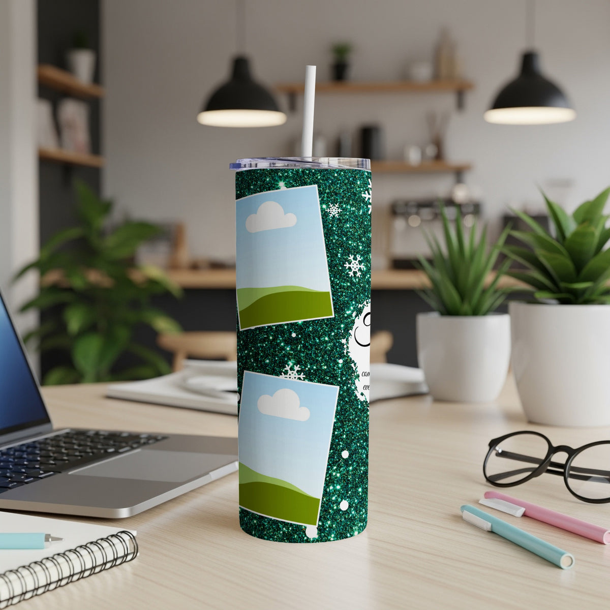 Glittery green tumbler with two photo frames and snowflakes on a desk.