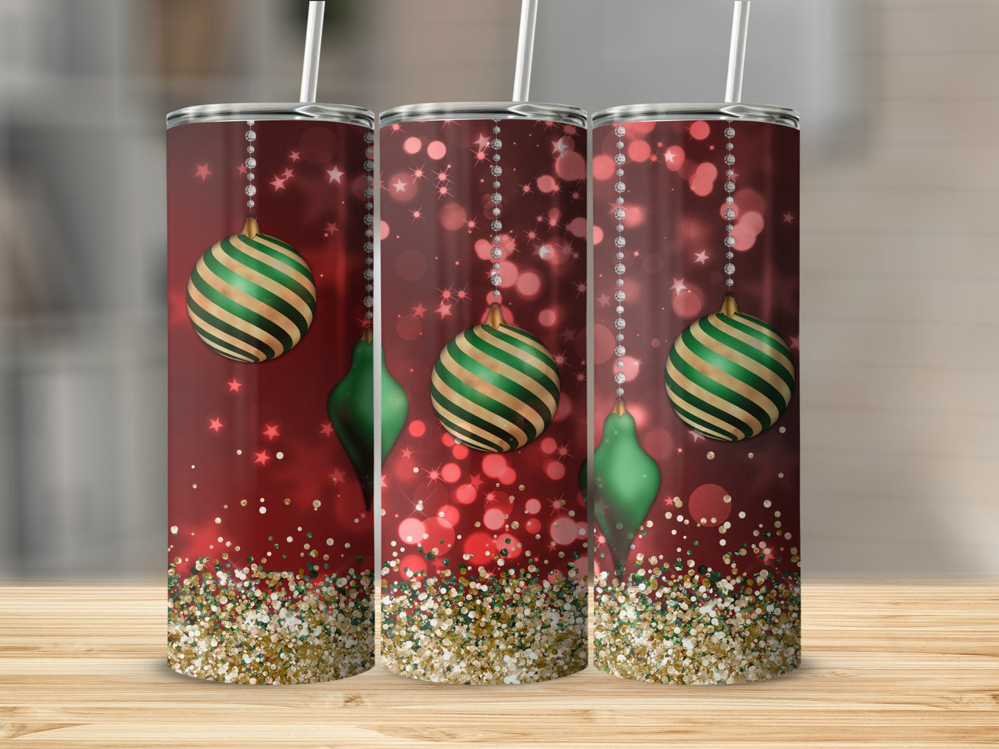 Three glitter tumblers with green and gold Christmas ornaments and bokeh lights.