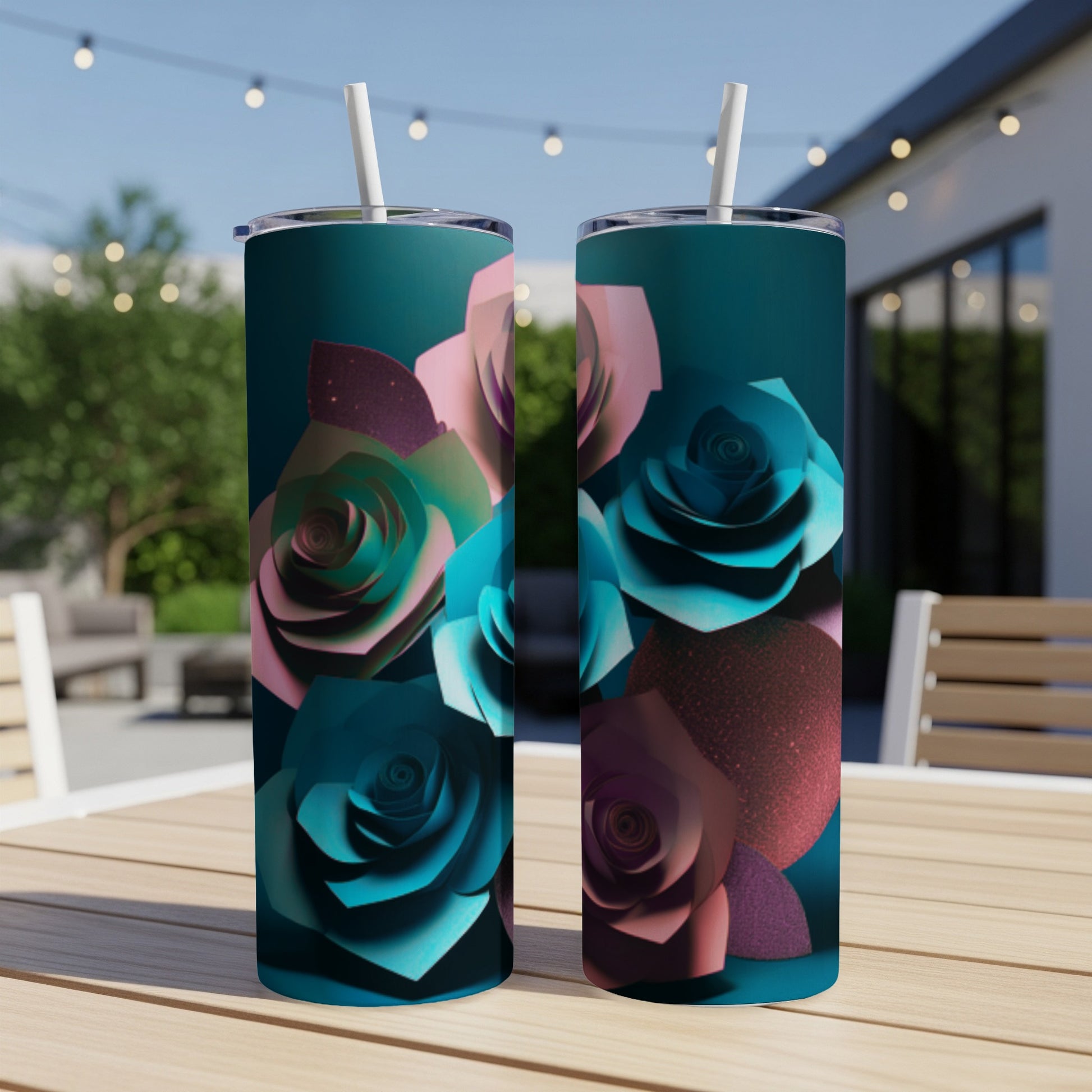 Two teal tumblers with paper roses design on an outdoor table.