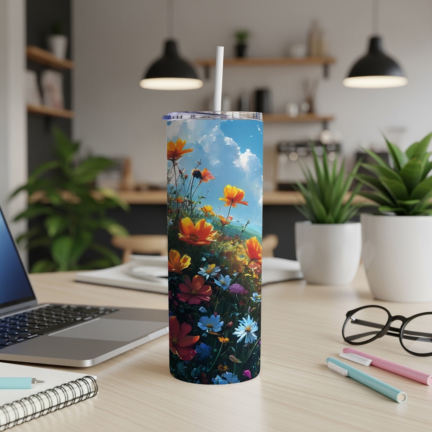 Floral design tumbler with straw on a desk next to a laptop.