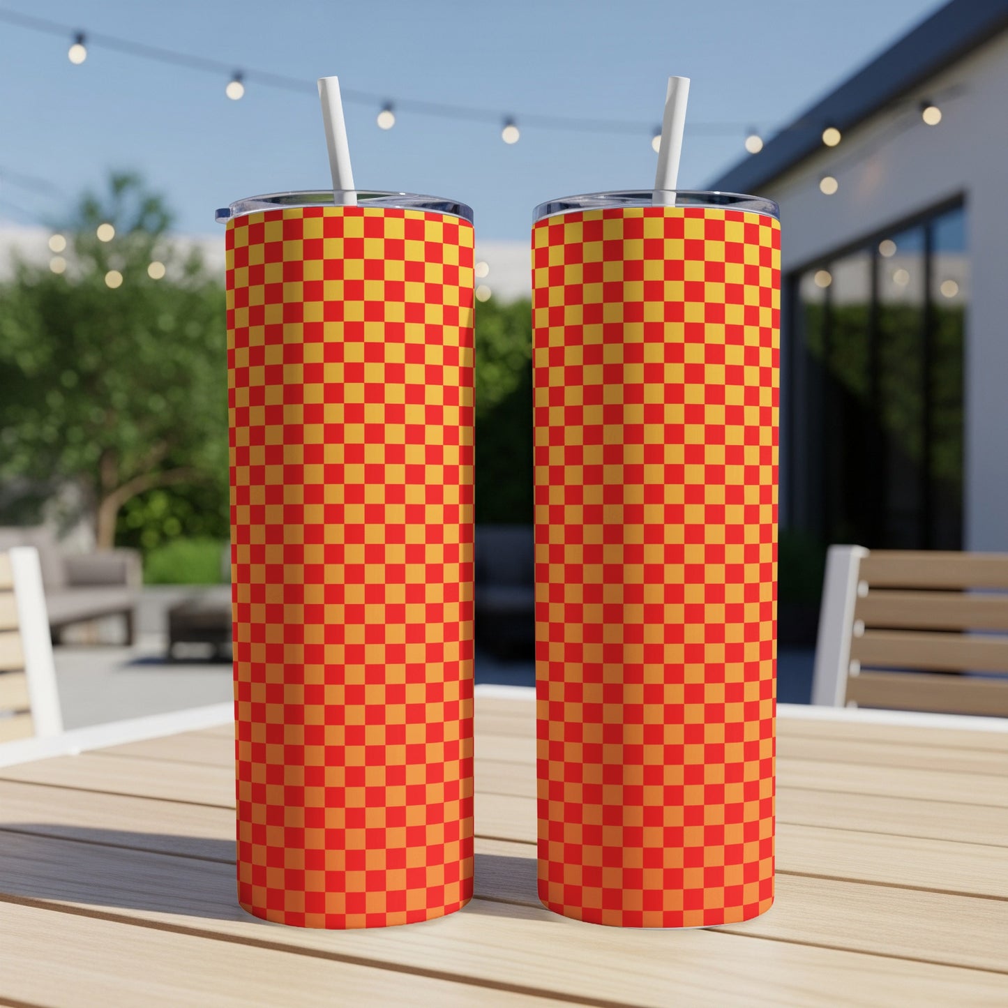 Two red and yellow checkered tumblers with straws on a wooden table.