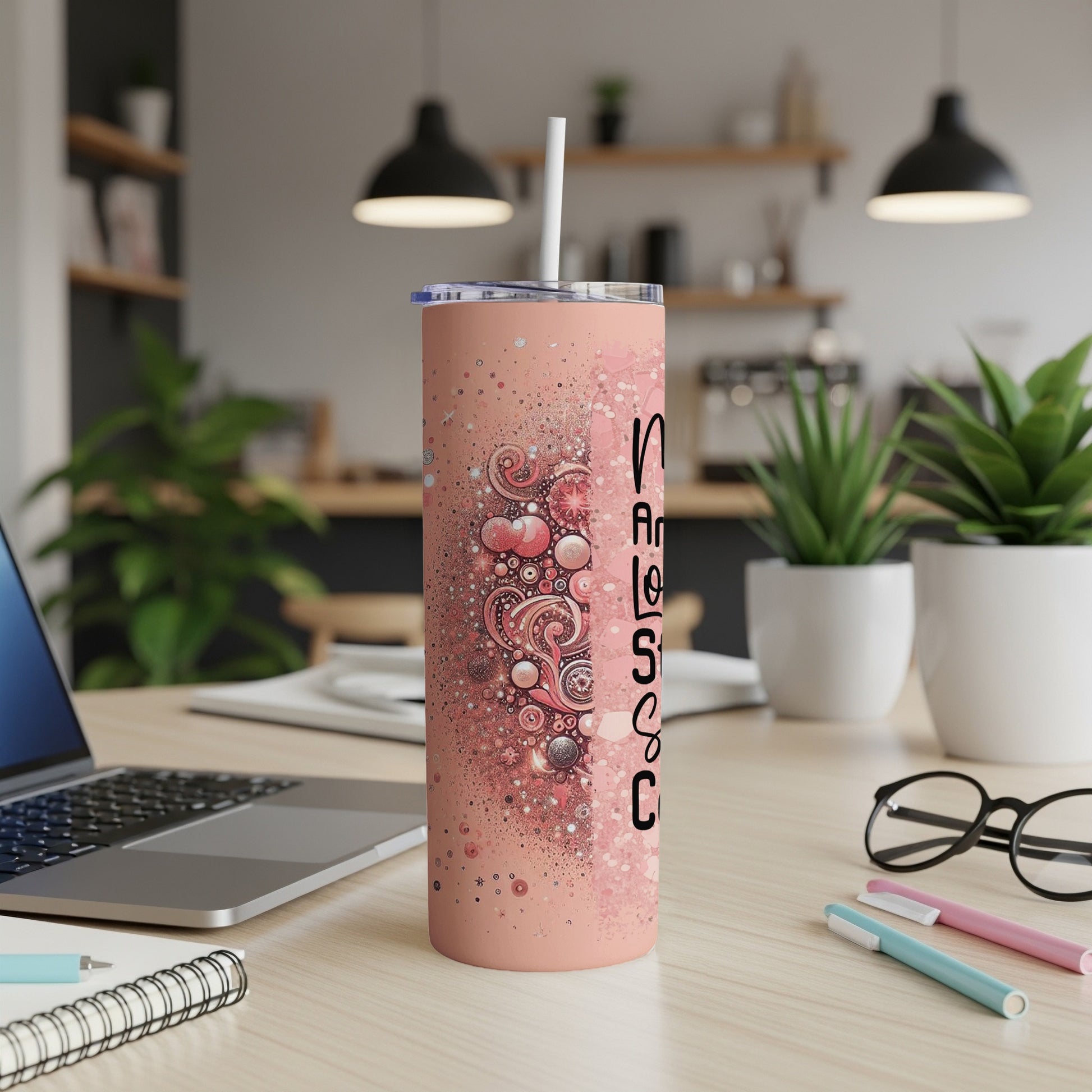 Pink tumbler with white straw on desk, featuring abstract heart and bubble design.