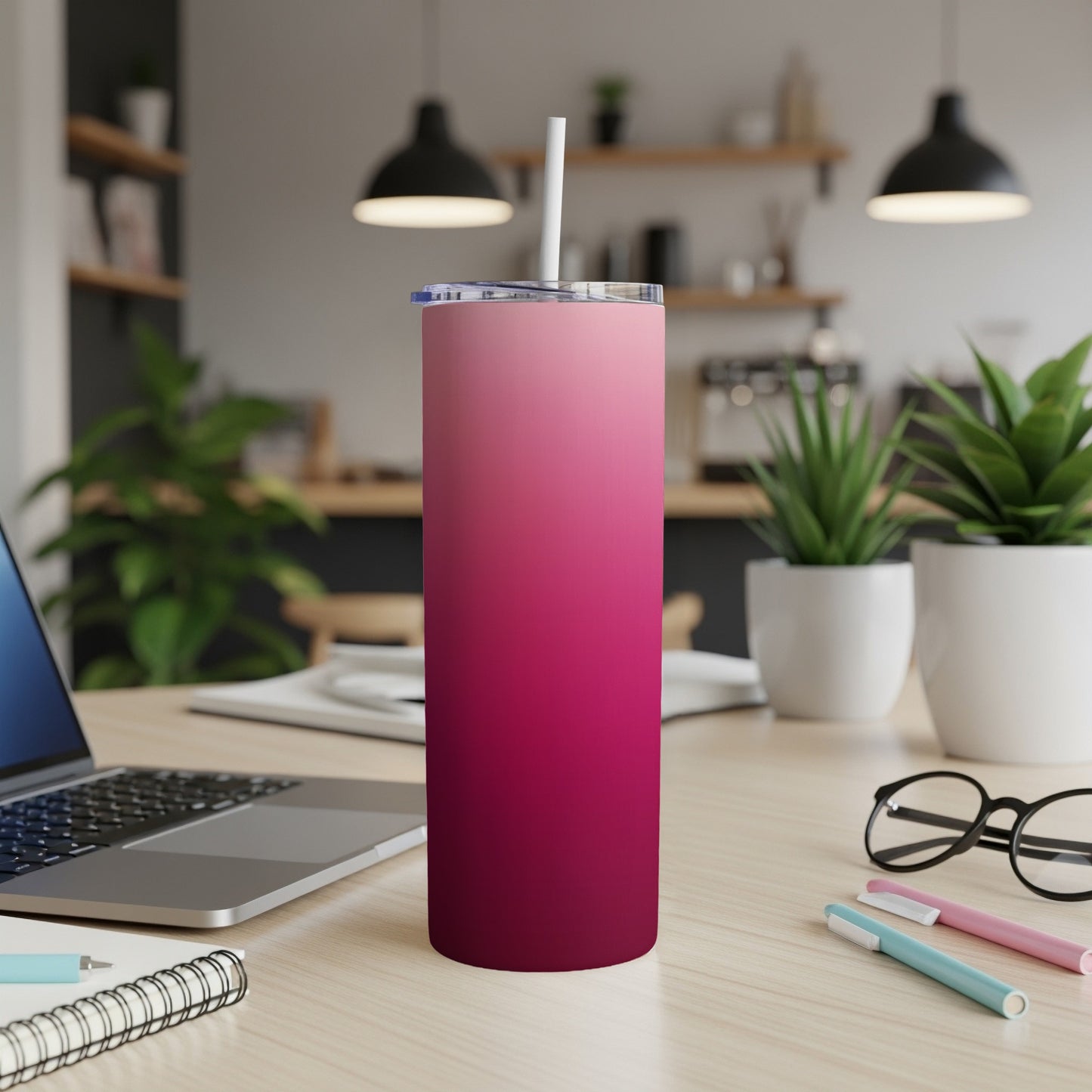 Pink to deep red ombre skinny tumbler with straw on desk.
