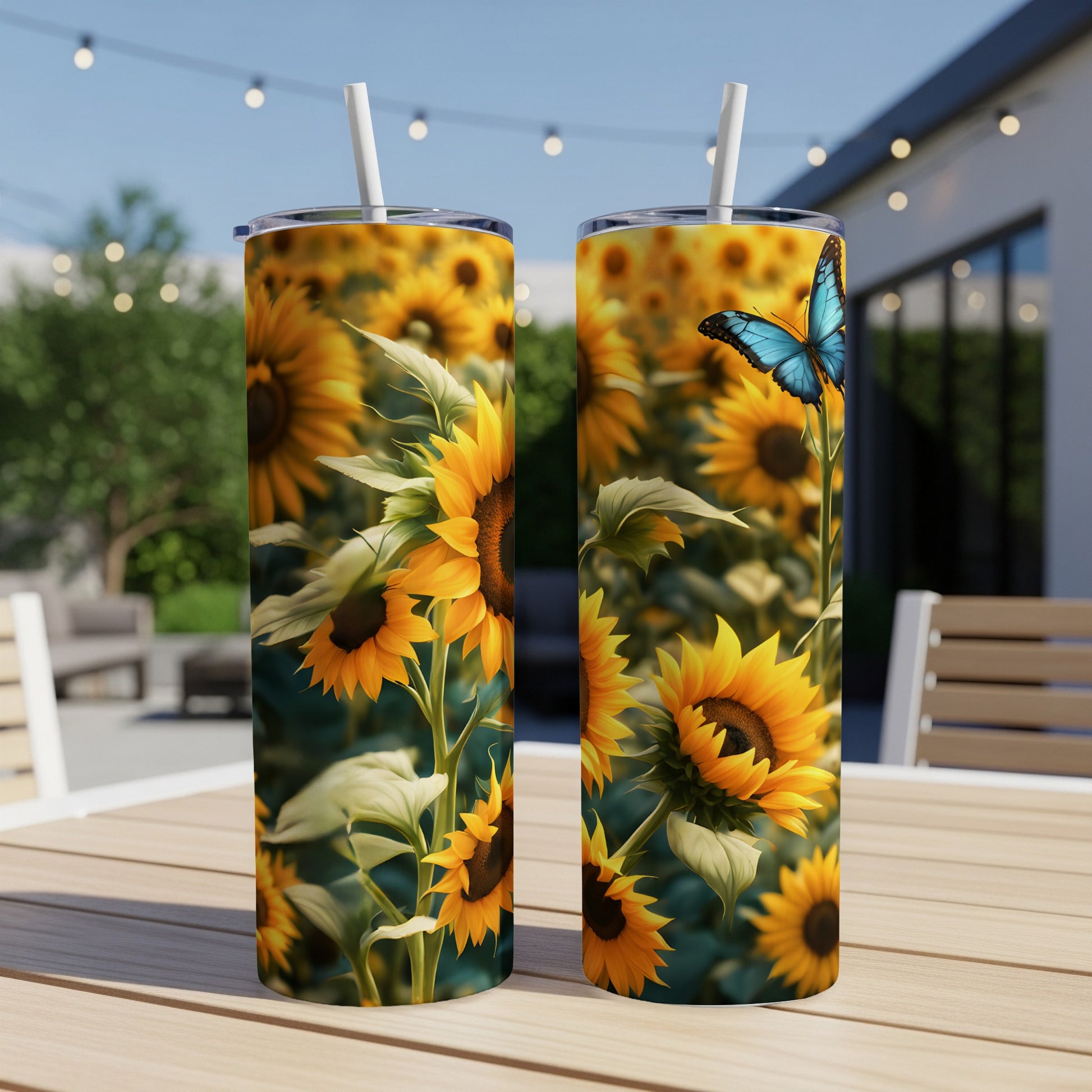 Two tumblers with sunflowers and a blue butterfly on a patio table.