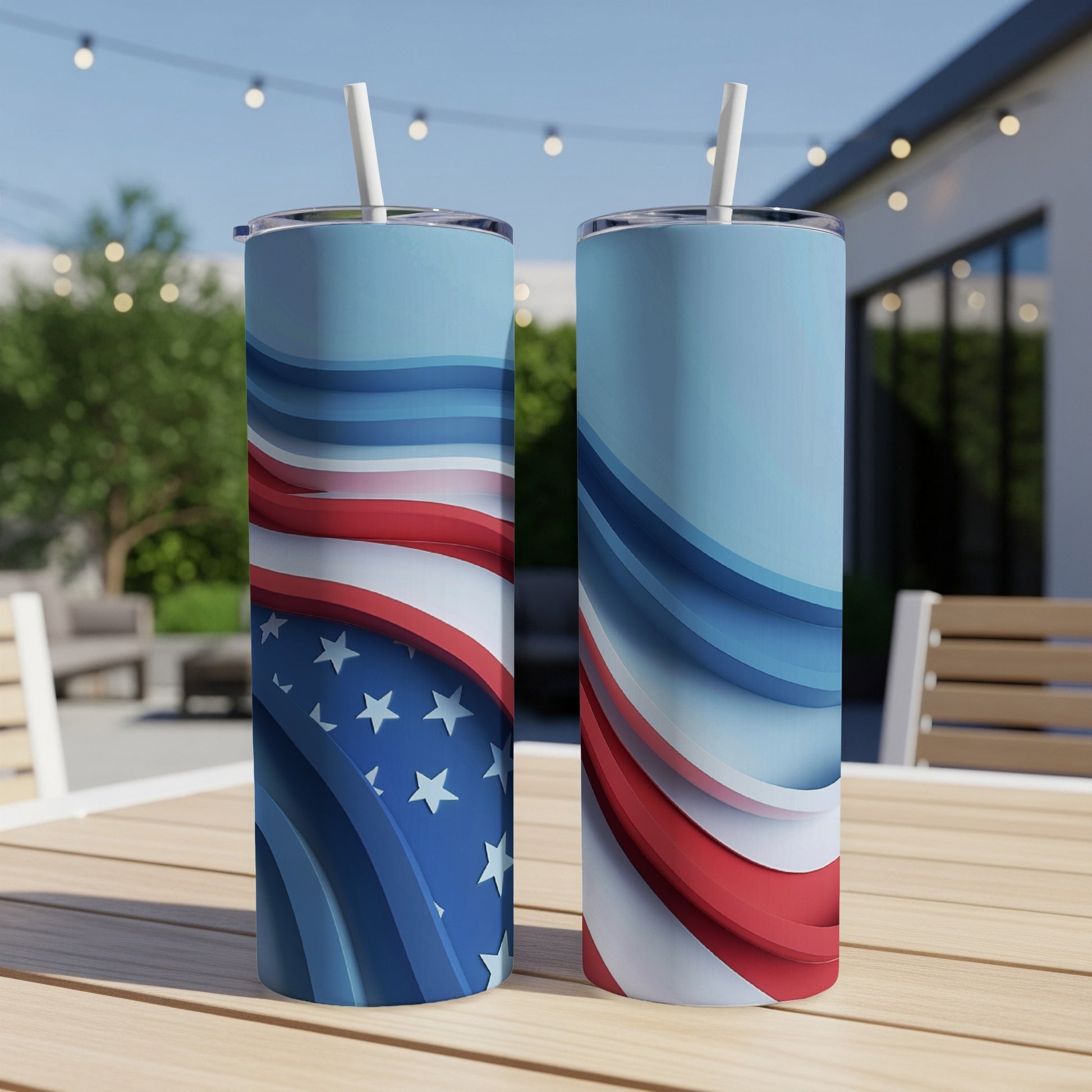 Two patriotic tumblers with American flag design on a wooden table outdoors.