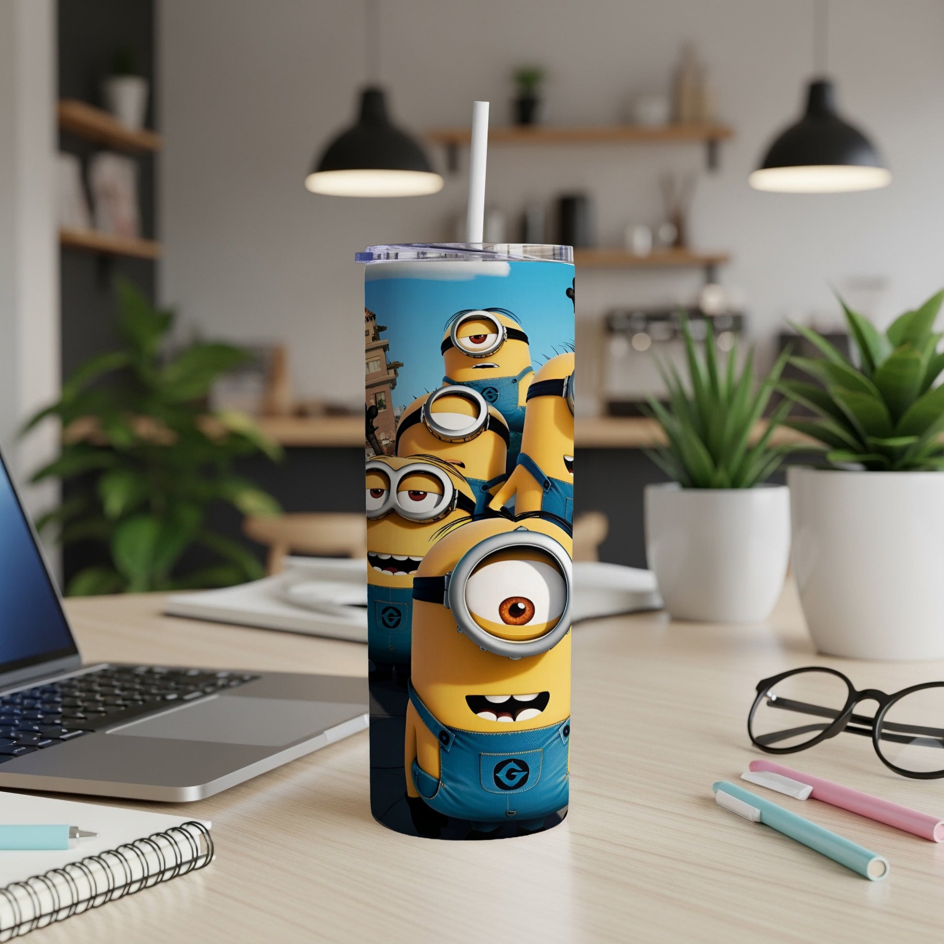 Minions in blue overalls on a tumbler with a straw, on a desk.