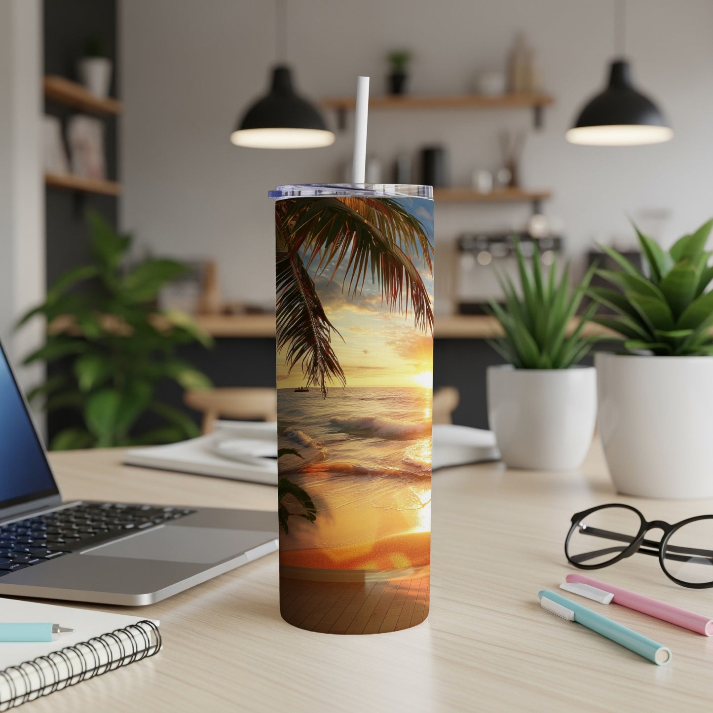 Sunset beach scene on a white tumbler with a straw on a desk.