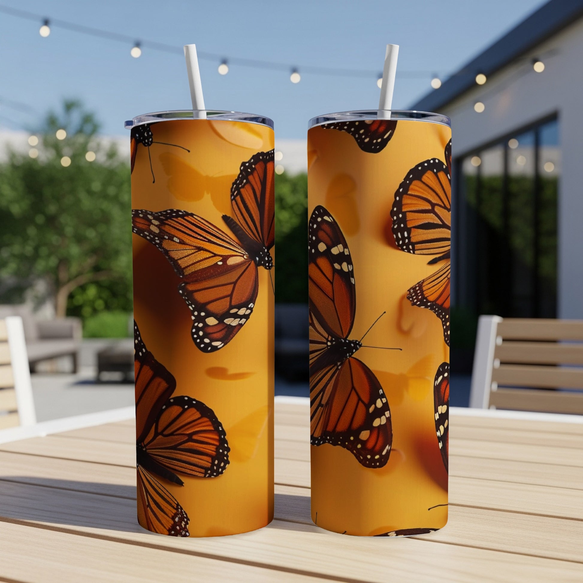 Two tumblers with monarch butterfly pattern on an outdoor table.