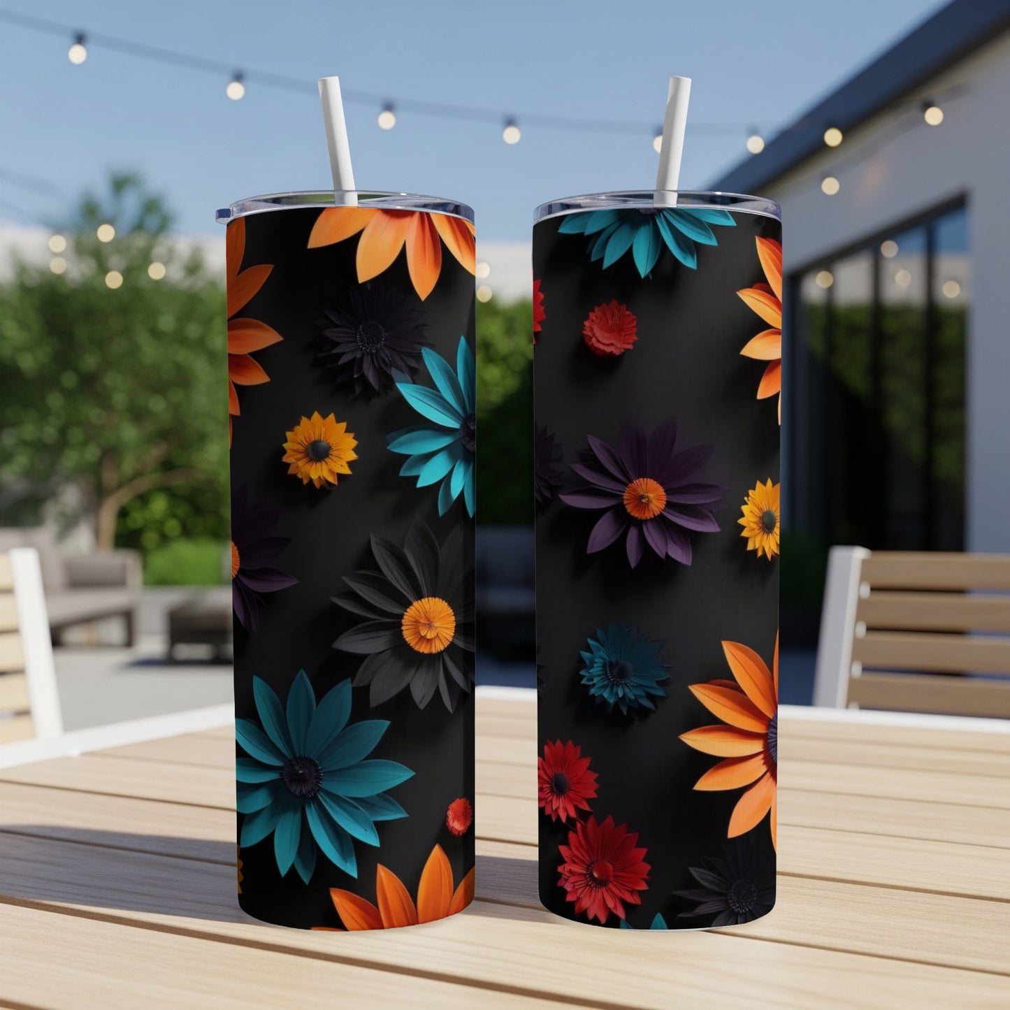 Two black tumblers with colorful floral designs displayed on an outdoor table.