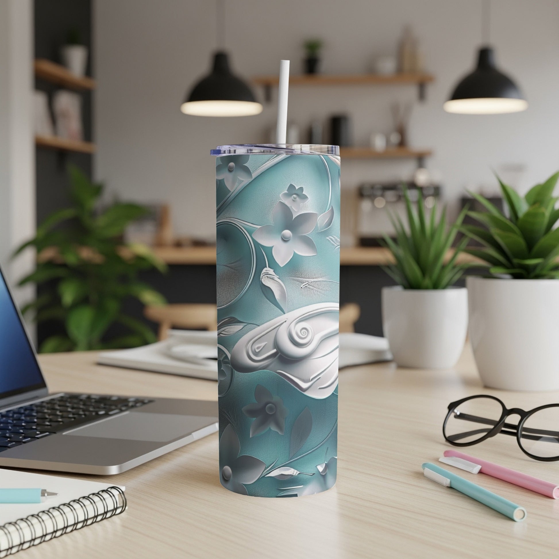 Blue floral patterned tumbler with straw on a desk next to a laptop.
