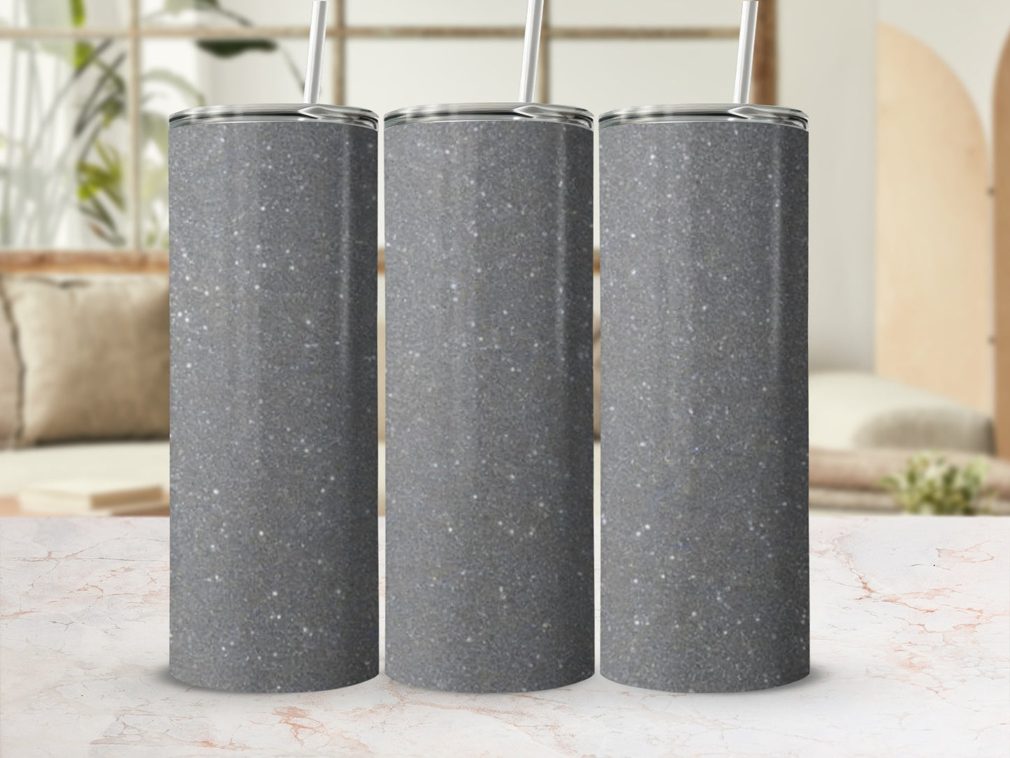 Three glittery gray tumblers with straws sit in a row.