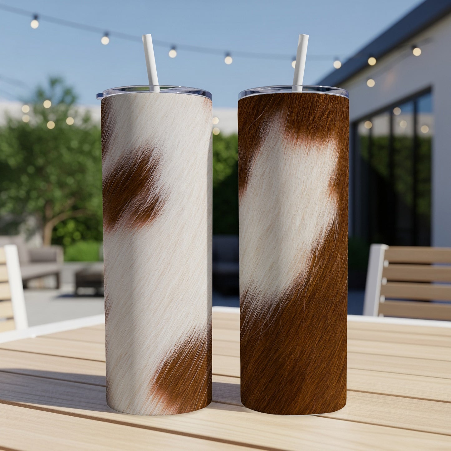 Two tall tumblers with brown and white cowhide patterns on a wooden table.
