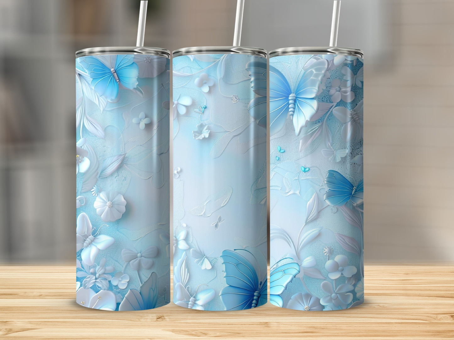Three light blue tumblers with butterfly and floral relief patterns on a wooden surface.