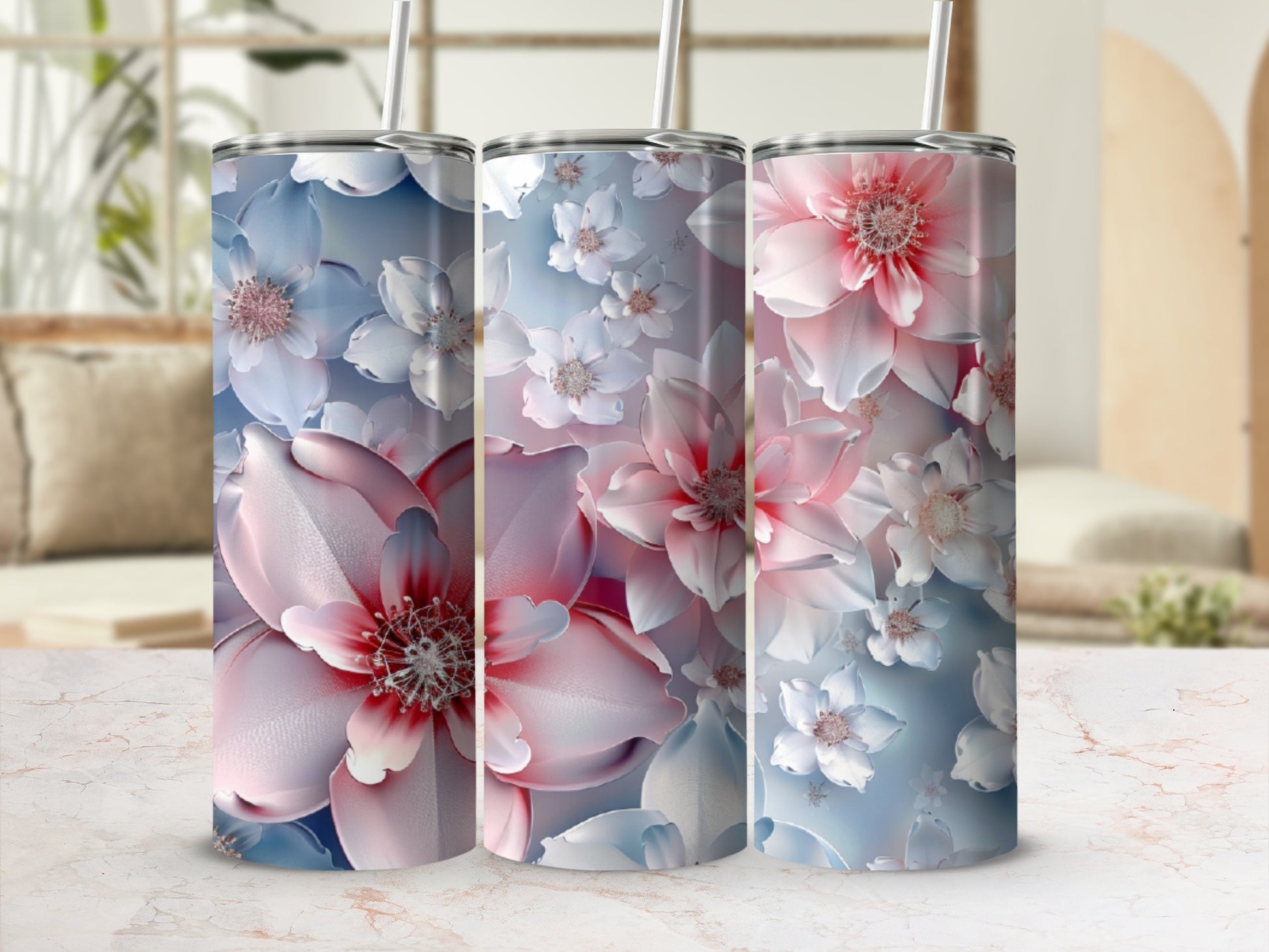 Three floral tumblers with pink and blue blossoms on a marble surface.