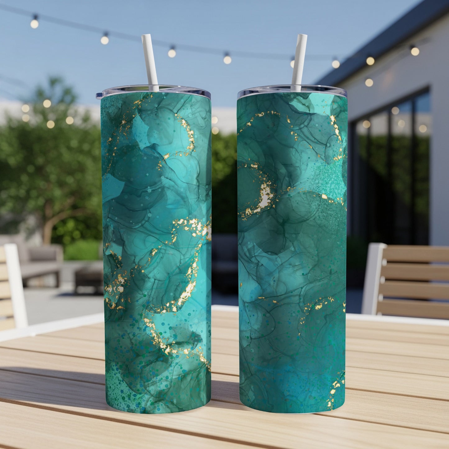 Two tumblers with teal and gold marbled abstract design on outdoor table.