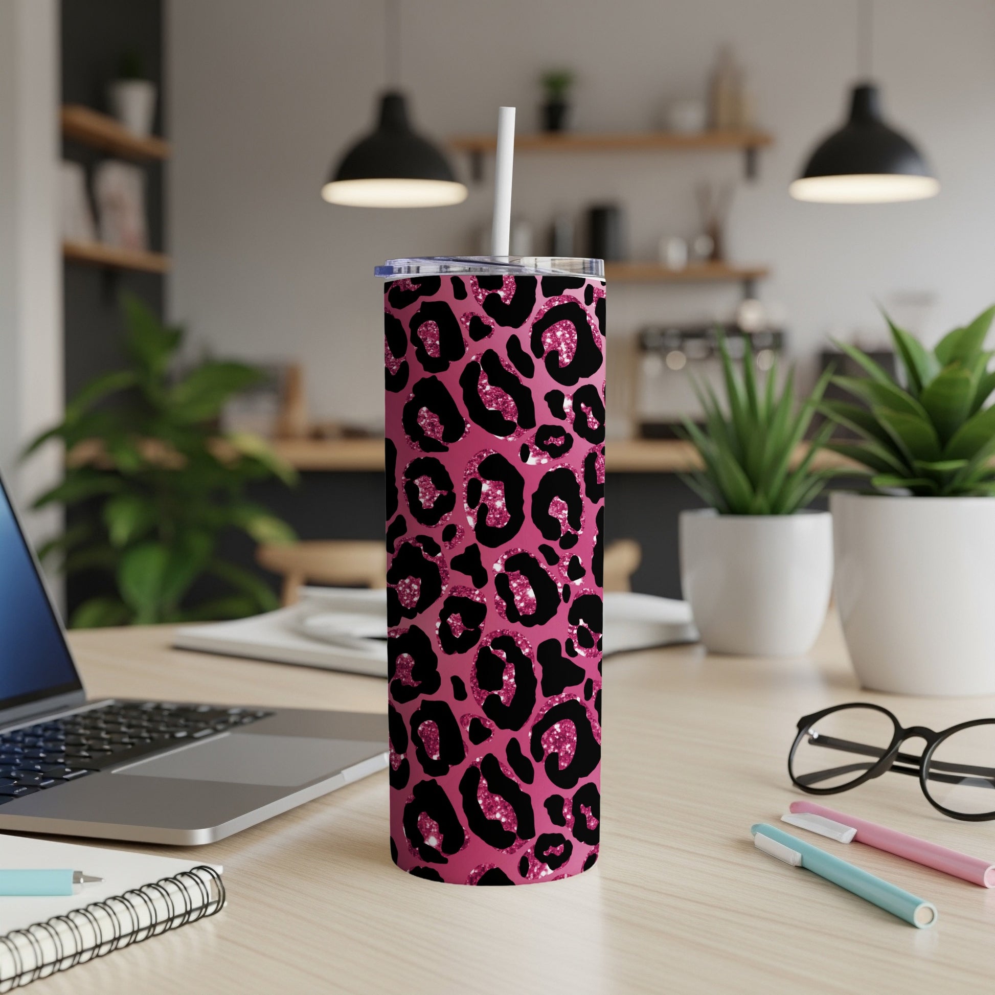 Pink leopard print tumbler with black spots and glitter accents, featuring a straw.