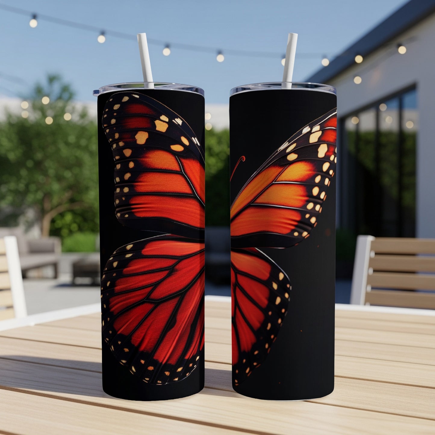 Two tall tumblers with a monarch butterfly wing design on a black background.