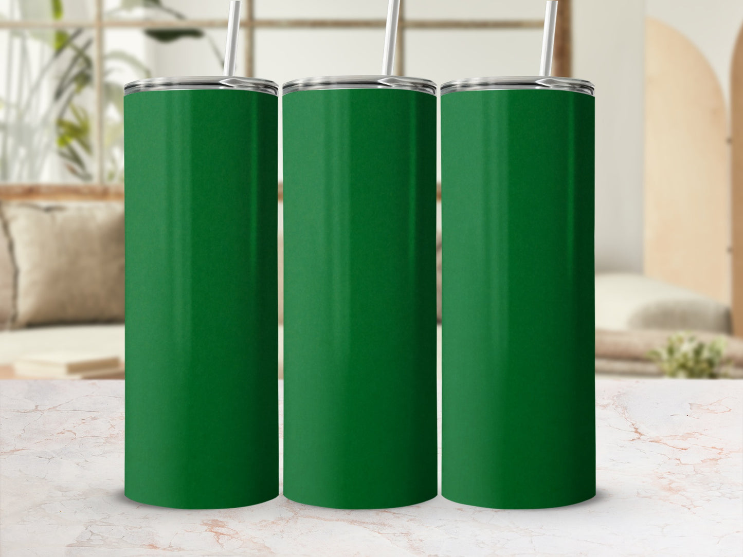 Three plain, tall, green tumblers with straws on a marble surface.