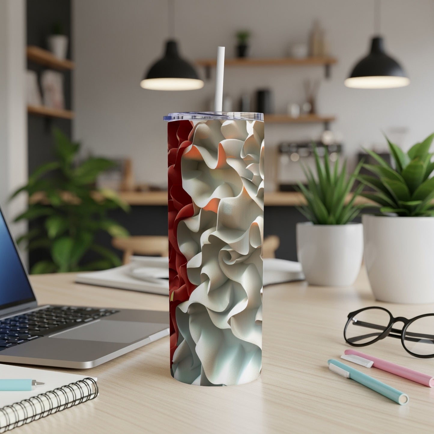 White and red floral patterned tumbler with straw on a desk.