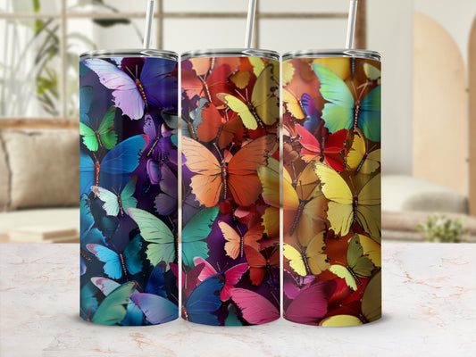 Three tumblers adorned with colorful butterfly patterns on a light marble surface.