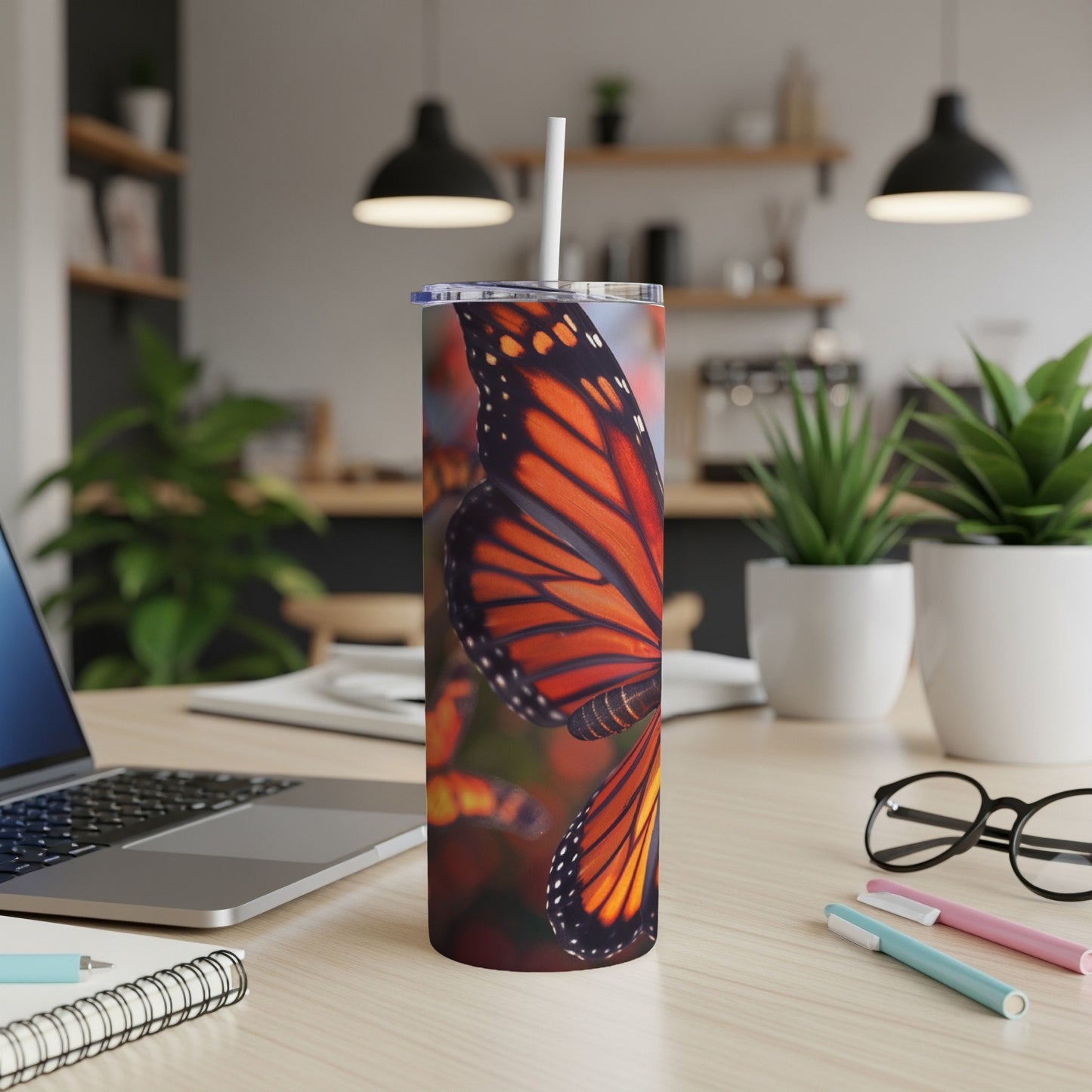 Monarch butterfly wing pattern on a white tumbler with a straw.