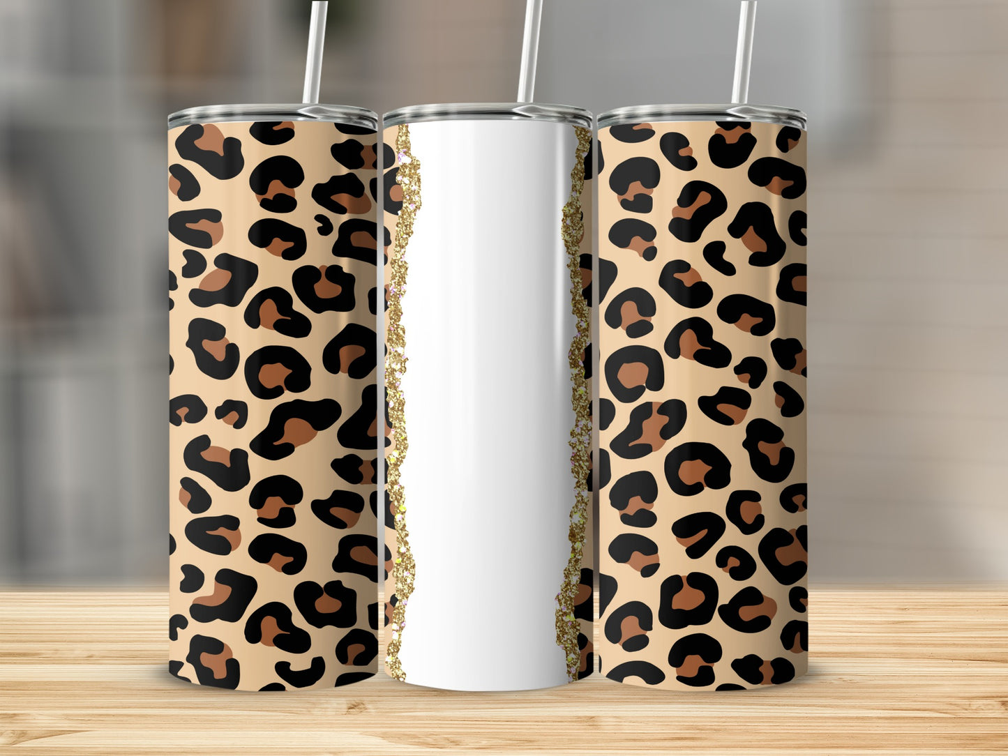 Three tumblers with leopard print and a sparkling gold trim on a wooden surface.